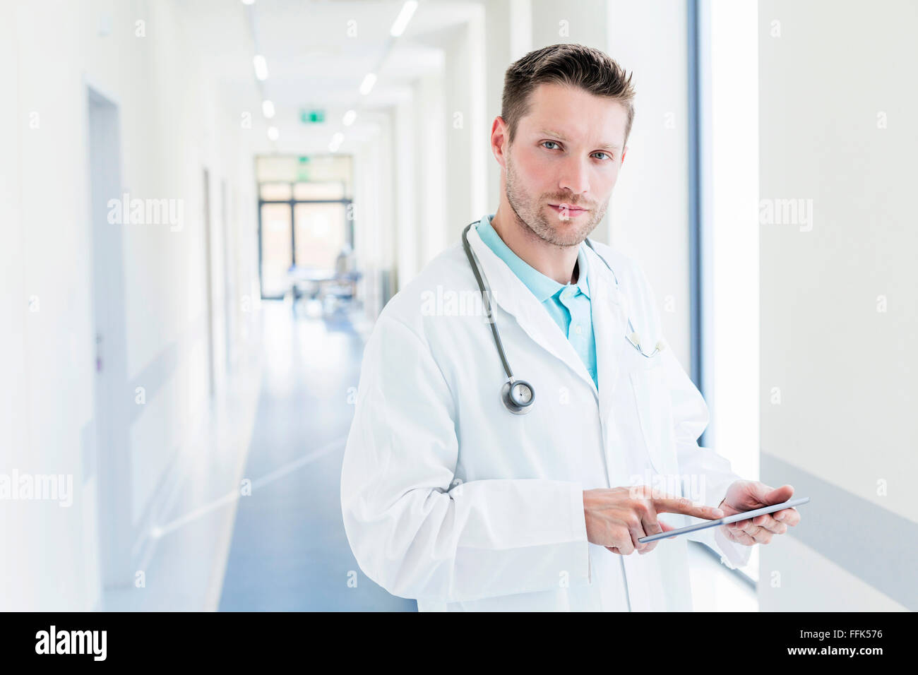 Medico in ospedale corridoio con tavoletta digitale Foto Stock