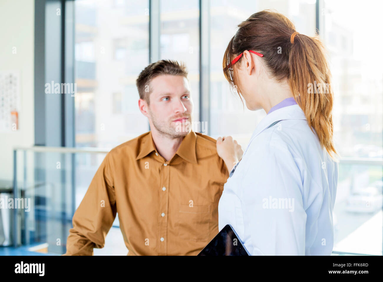 Medico donna toccando il paziente sulla spalla Foto Stock