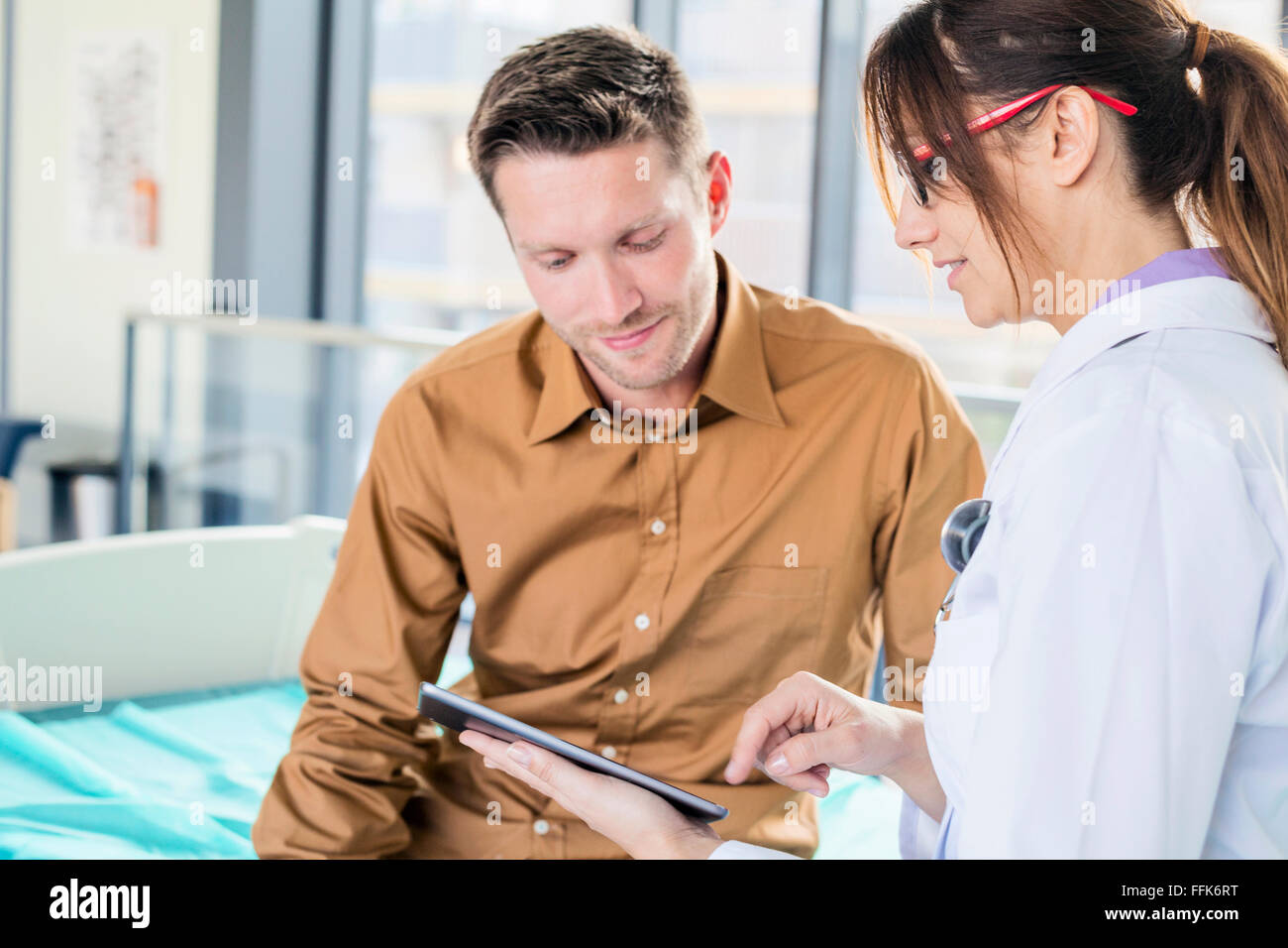Femmina il medico e il paziente guardando a tavoletta digitale Foto Stock