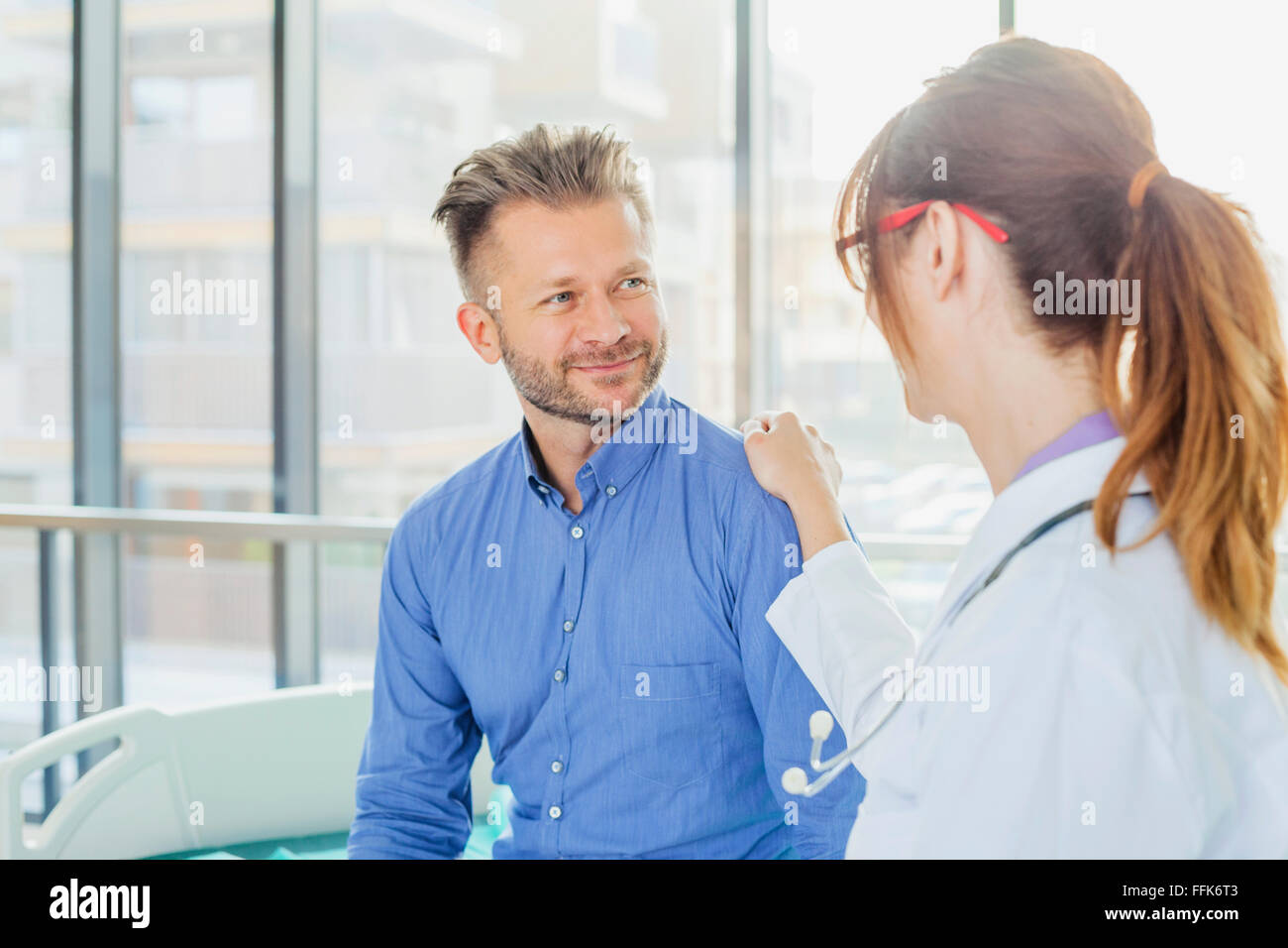 Medico donna toccando il paziente sulla spalla Foto Stock