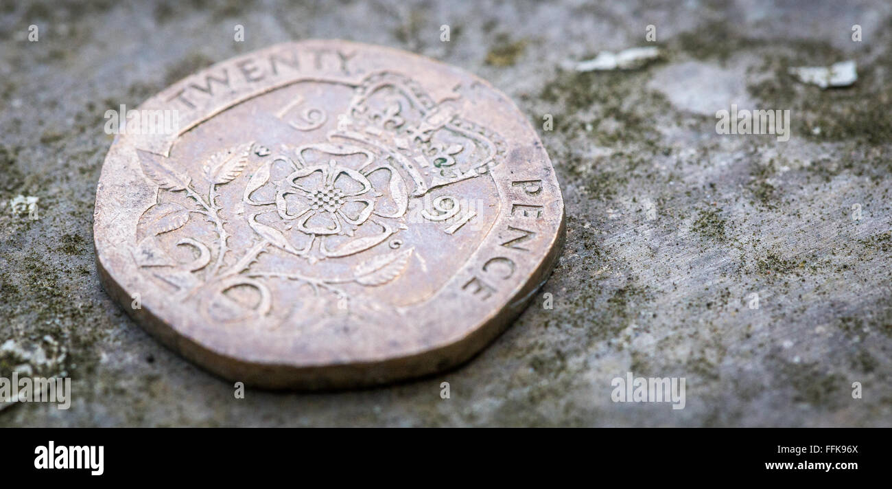 Macro Immagine ravvicinata di 20p venti pence su un ripiano in metallo con polvere di verde su uno sfondo metallico Foto Stock