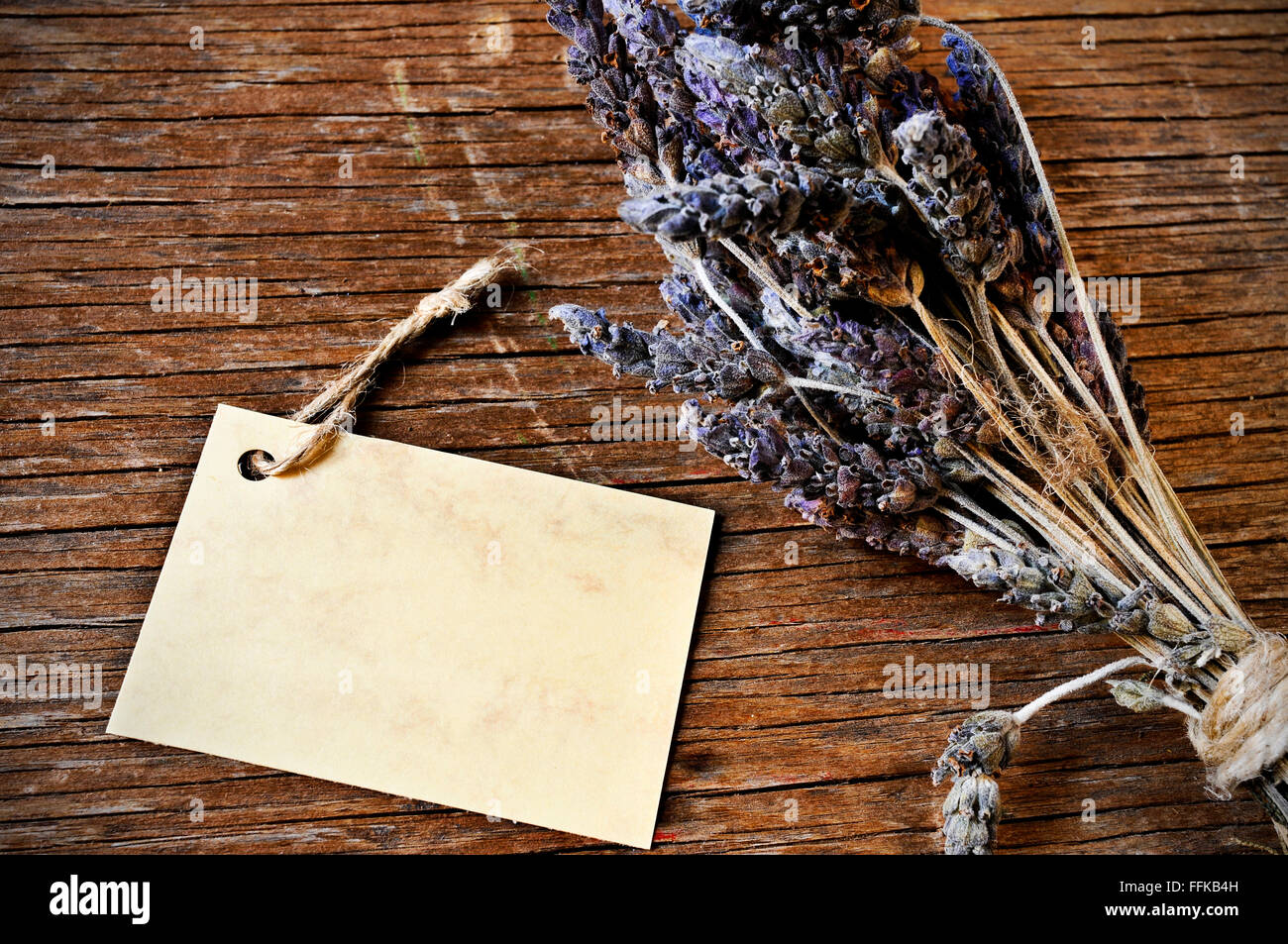 Primo piano di un mazzo di fiori di lavanda legato con una corda e un cartone vuoto cartello su un rustico di una superficie di legno Foto Stock