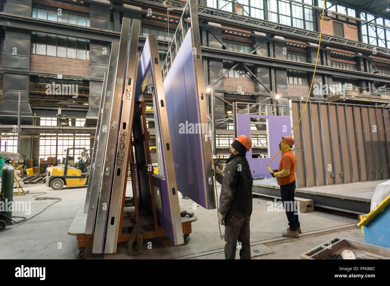 Lavoratori manovra una parete in posizione di alloggiamento modulare in una fabbrica in Brooklyn Navy Yard a New York il giovedì, 11 febbraio 2016. A causa dell aumento degli affitti e la necessità di un servizio specializzato di spazio la fabbrica sarà la chiusura dopo dopo questo processo, alloggiamento per la molla di Neemia Creek allo sviluppo. Steiner Studios, un altro locatario presso il Brooklyn Navy Yard sarà tenuto oltre lo spazio. (© Richard B. Levine) Foto Stock