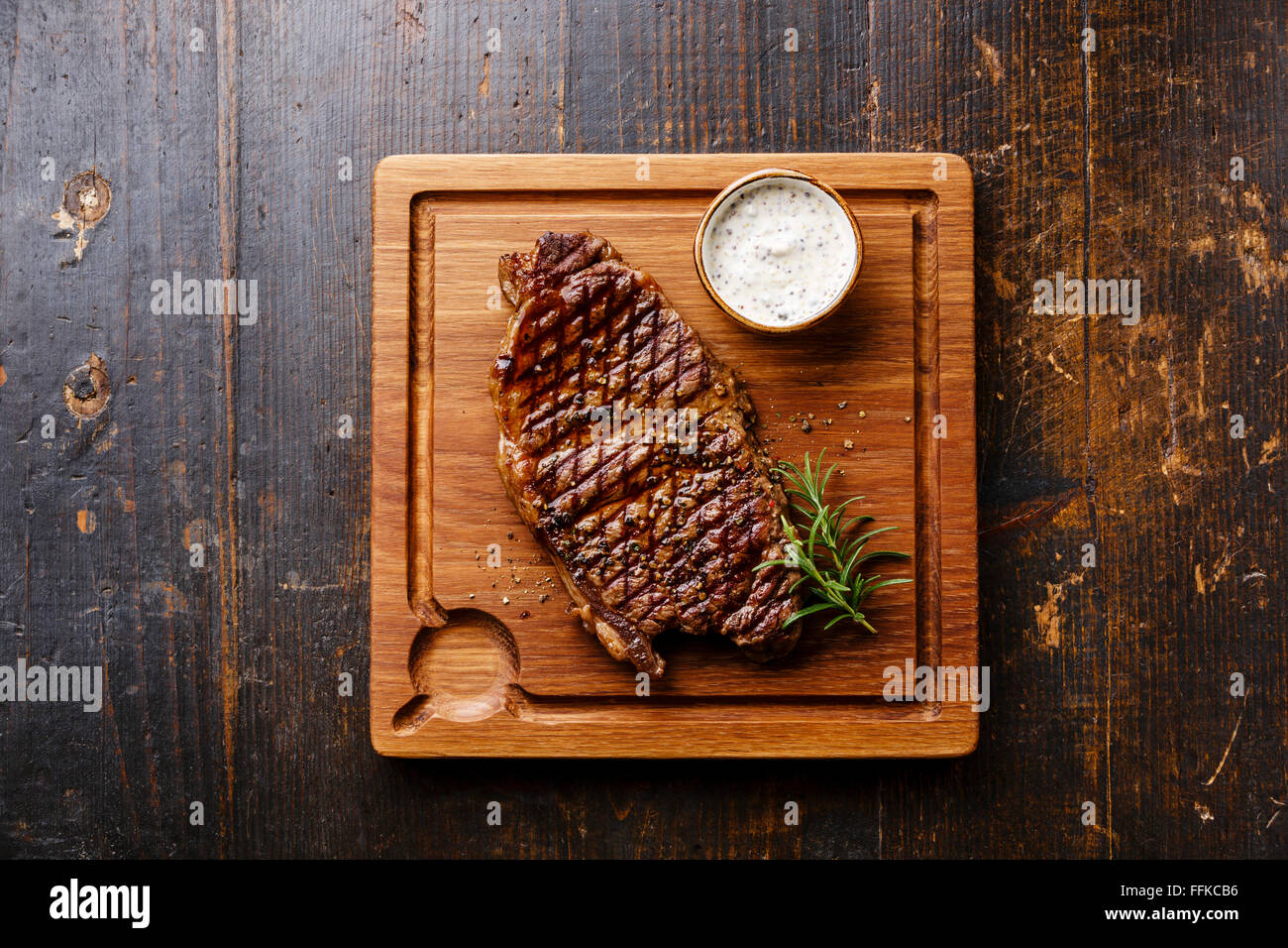 Bistecca alla griglia controfiletto e salsa di peperoni sul tagliere in legno scuro dello sfondo Foto Stock