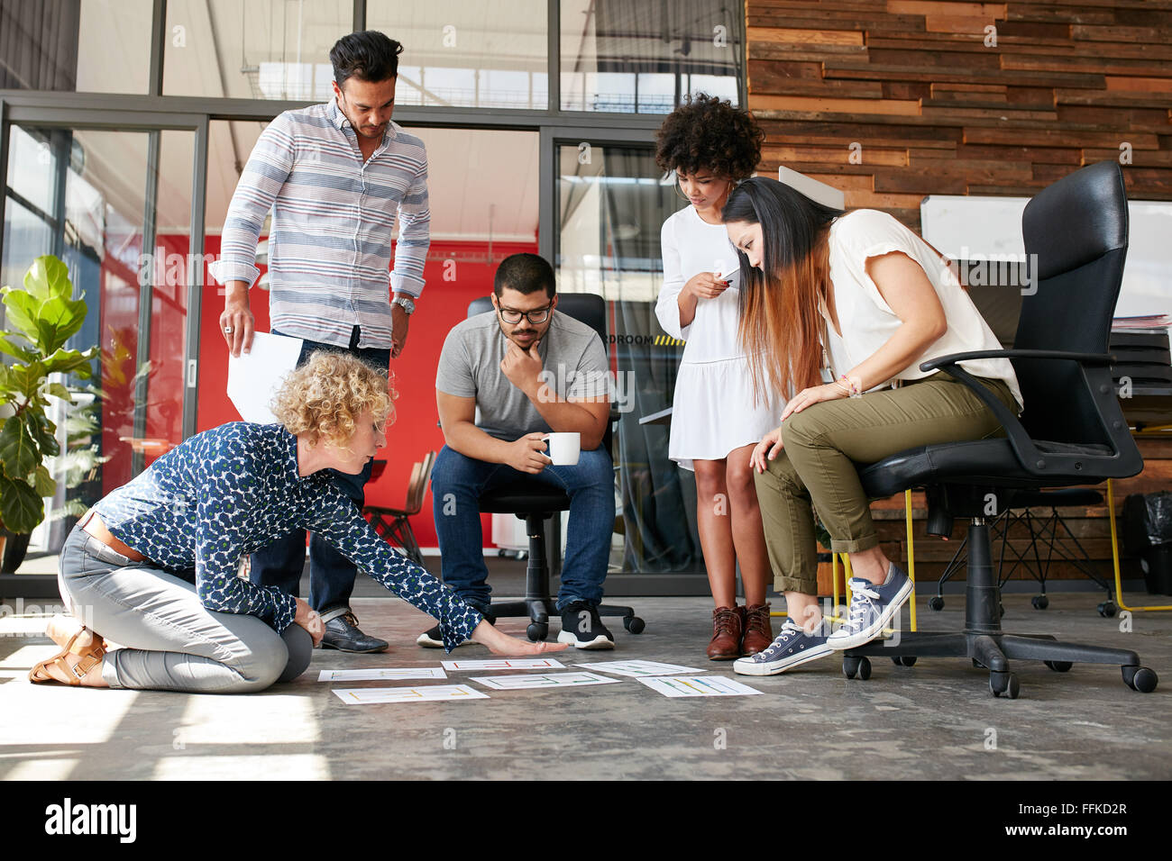 Le persone creative che guardando il piano di progetto disteso sul pavimento. Razza mista business associates a discutere di un nuovo piano di progetto nei moderni Foto Stock