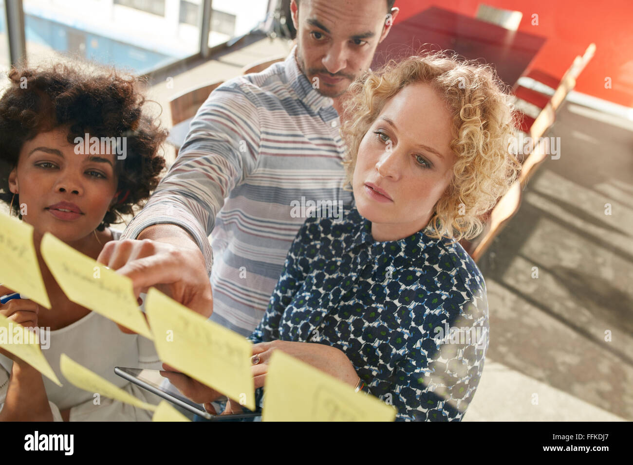 Ritratto di professionisti creativi cercando su un postit nota parete e di brainstorming. Giovani uomini e donne in piedi presso l'ufficio Foto Stock