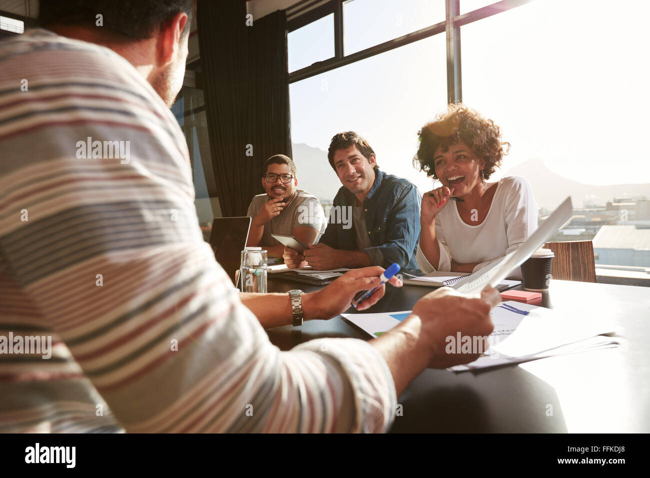 Colpo di razza mista giovani seduti ad un tavolo per discutere nuove e creative idee di business. Sorridente donna africana seduta wit Foto Stock