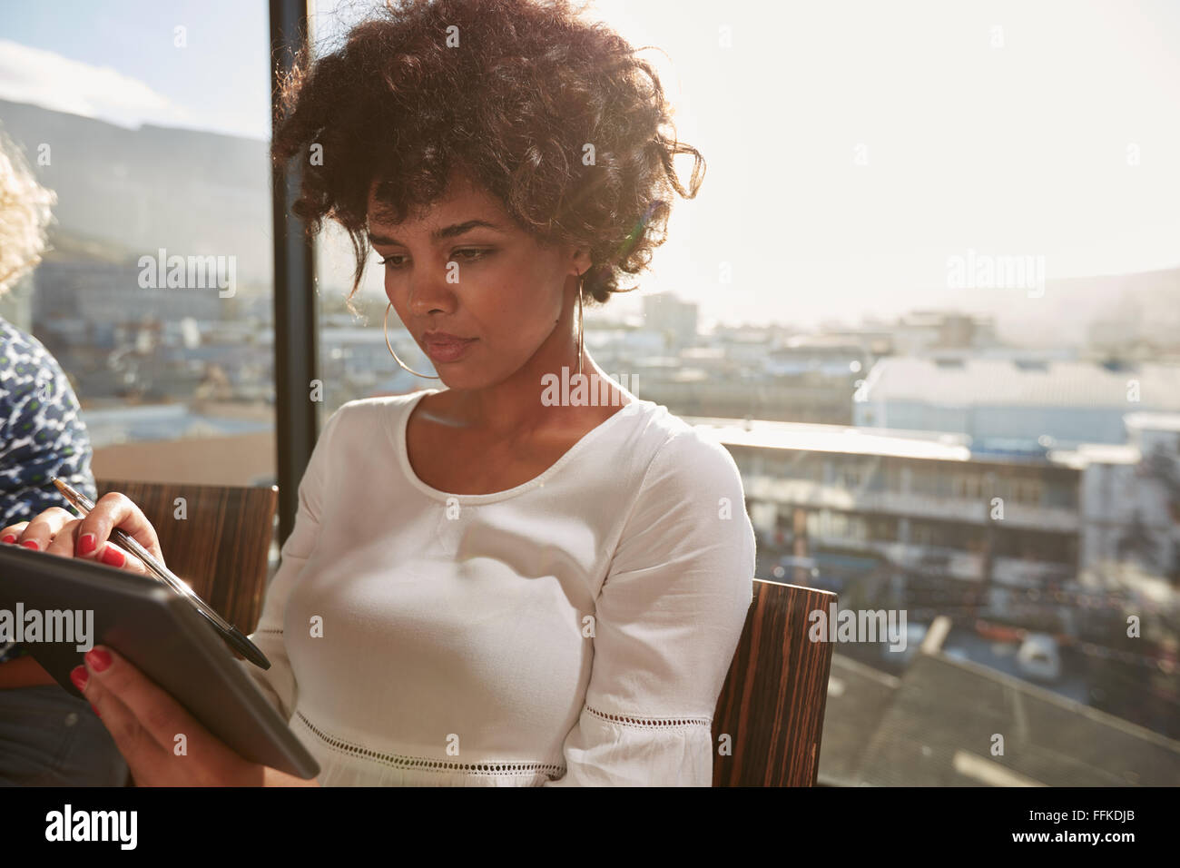Ritratto di giovane donna africana seduto in ufficio utilizzando digitale compressa. Attraente imprenditrice navigando in internet sul suo tablet Foto Stock