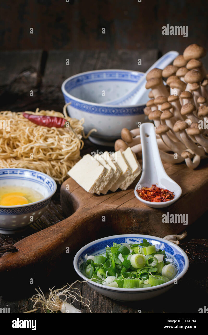 Ingredienti per asian ramen zuppa. Tagliatelle, cipolline, il formaggio feta, funghi, uova e peperoncino in asian porcelan bocce ov Foto Stock