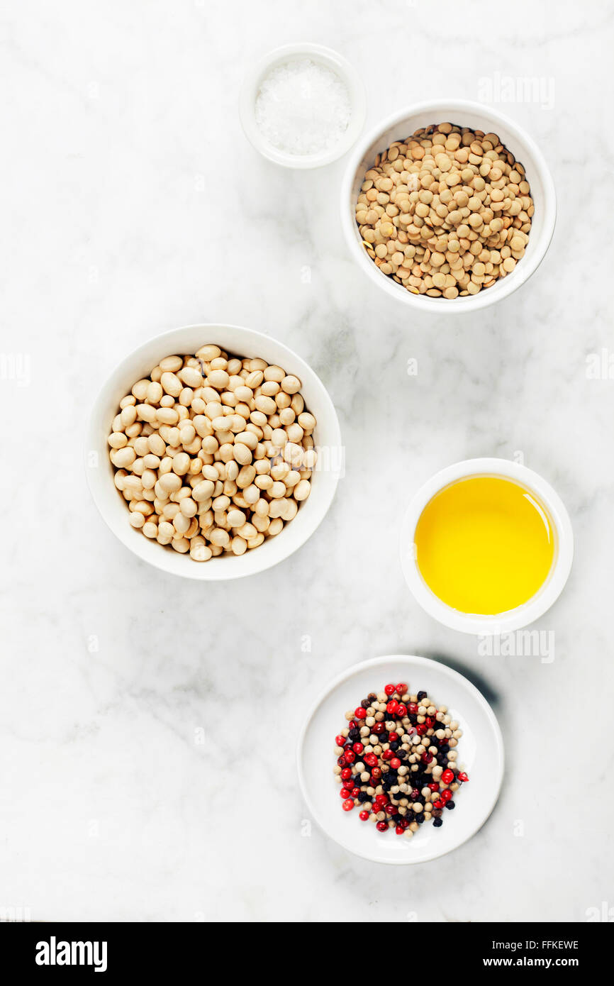 Tettuccio di colpo di lenticchie, fagioli, olio d'oliva, sale e pepe e rustico tavolo in marmo. Foto Stock