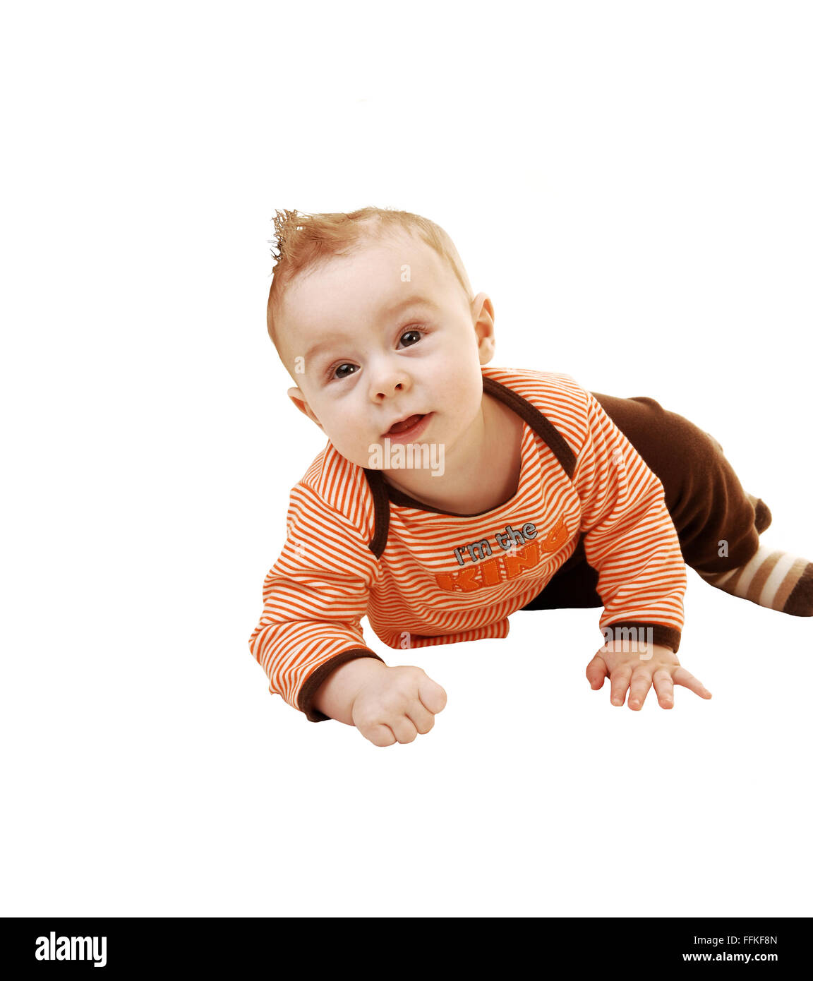 Un dolce piccolo bimbo gattona sul pavimento in lui maglione arancione e marrone e pantaloni, esaminando la fotocamera per lo sfondo bianco Foto Stock