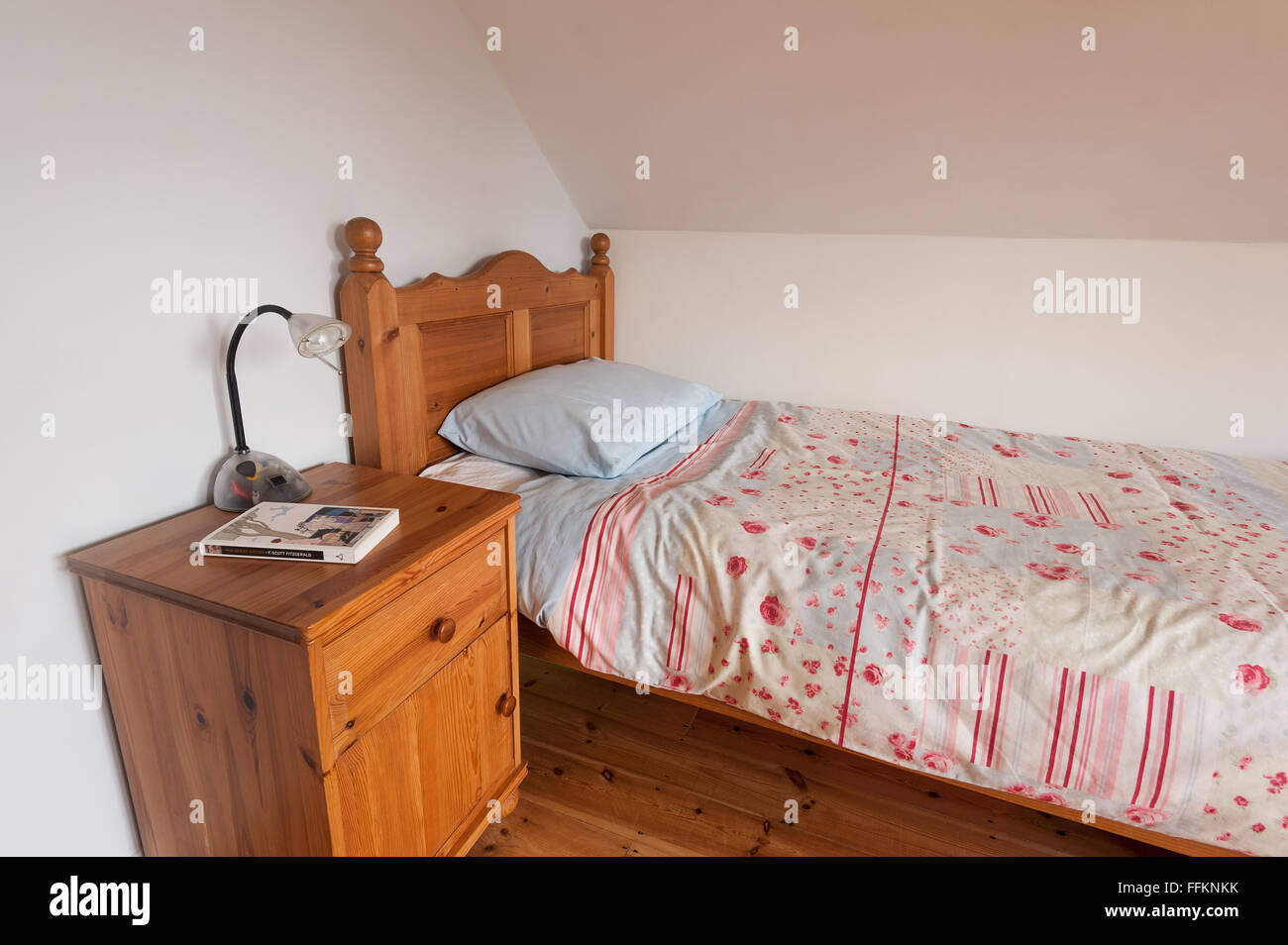 Neat pino di legno letto e piumone con armadio e la spia Pronta per una buona lettura al posto letto di un romanzo Foto Stock