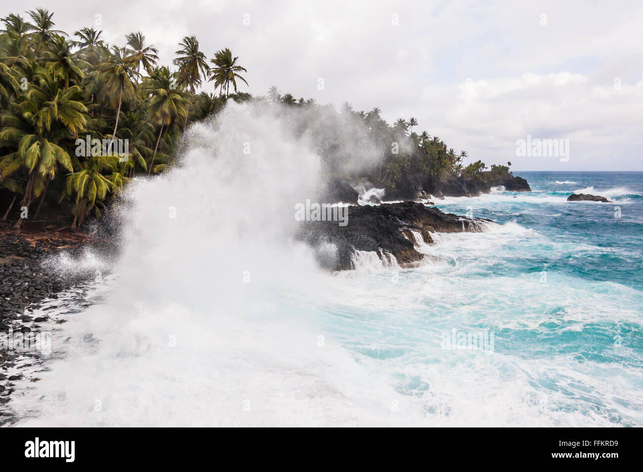 Grandi onde schiacciamento sulla riva di un'isola tropicale con palme durante una tempesta. Praia Piscina - Sao Tomè e Principe. Foto Stock
