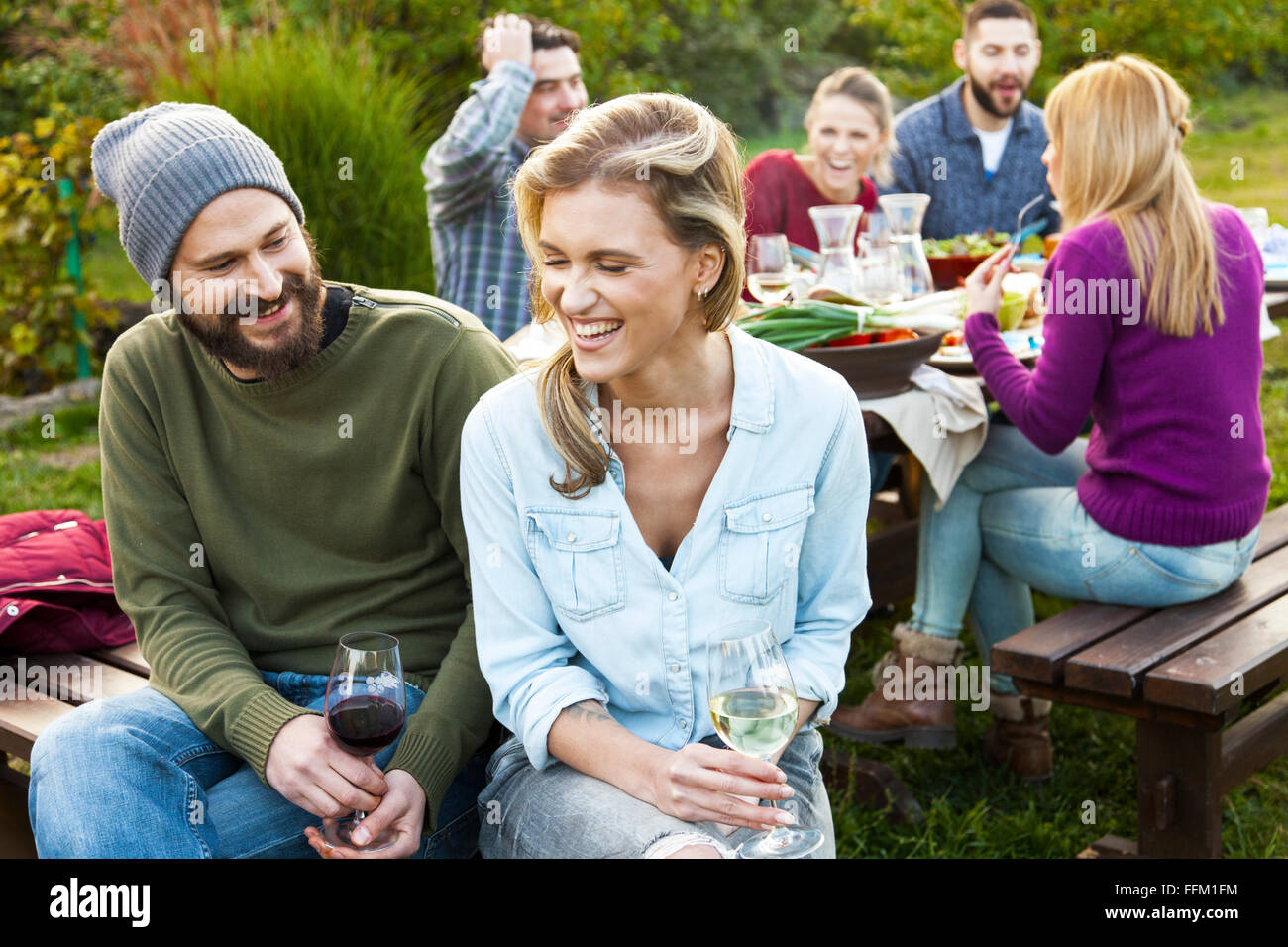 Gruppo di amici bevendo vino su party in giardino Foto Stock