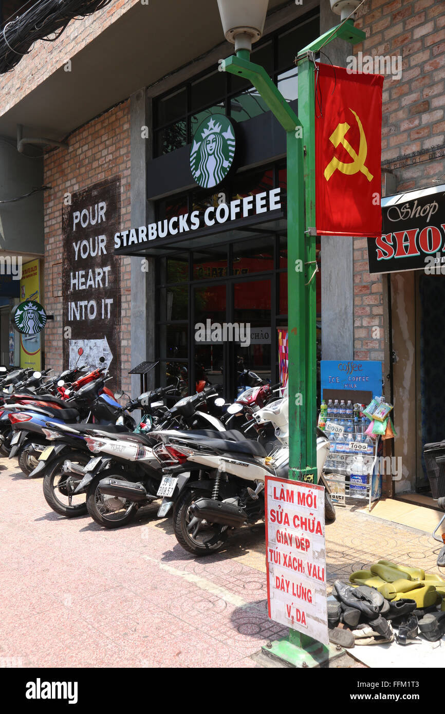 La miscela di vietnamiti del comunismo e capitalismo è illustrato in una strada a Ho Chi Minh City, dove uno Starbucks è accanto a Foto Stock