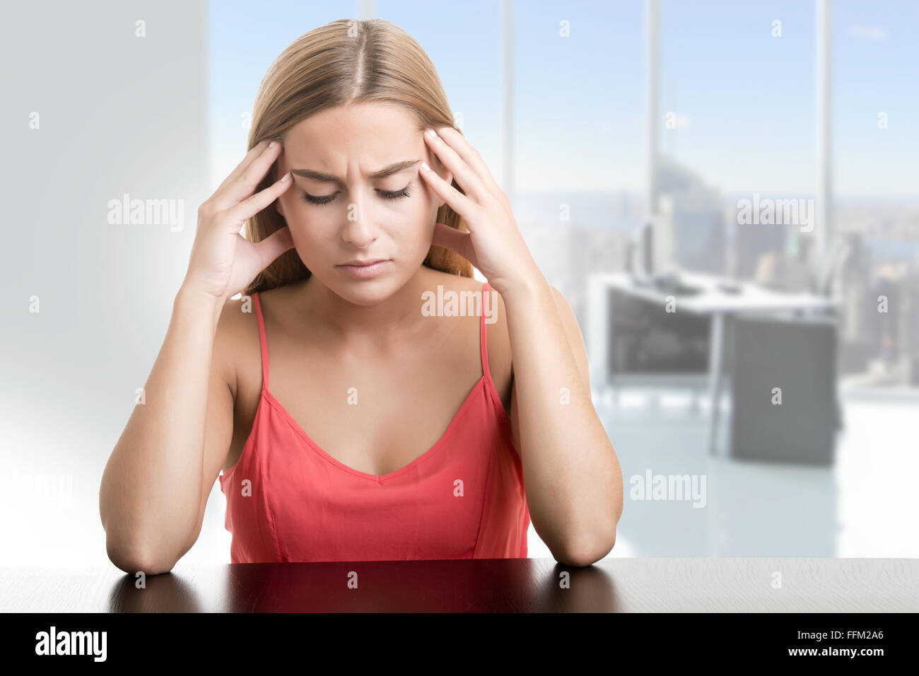 La donna che soffre di un mal di testa, tenendo la mano alla testa, in un ufficio Foto Stock