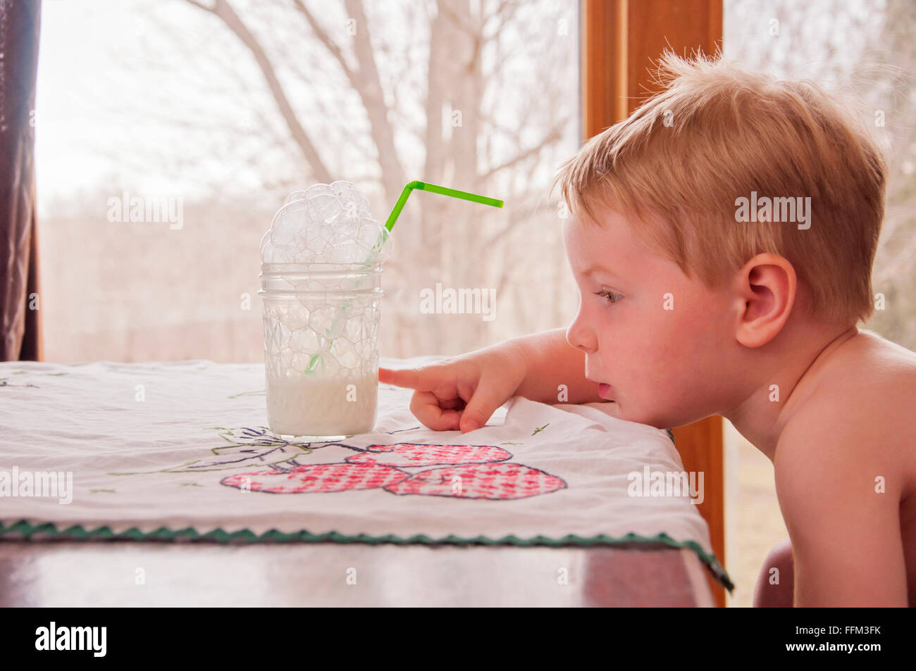 Bambino puntando al bicchiere mezzo pieno Foto Stock