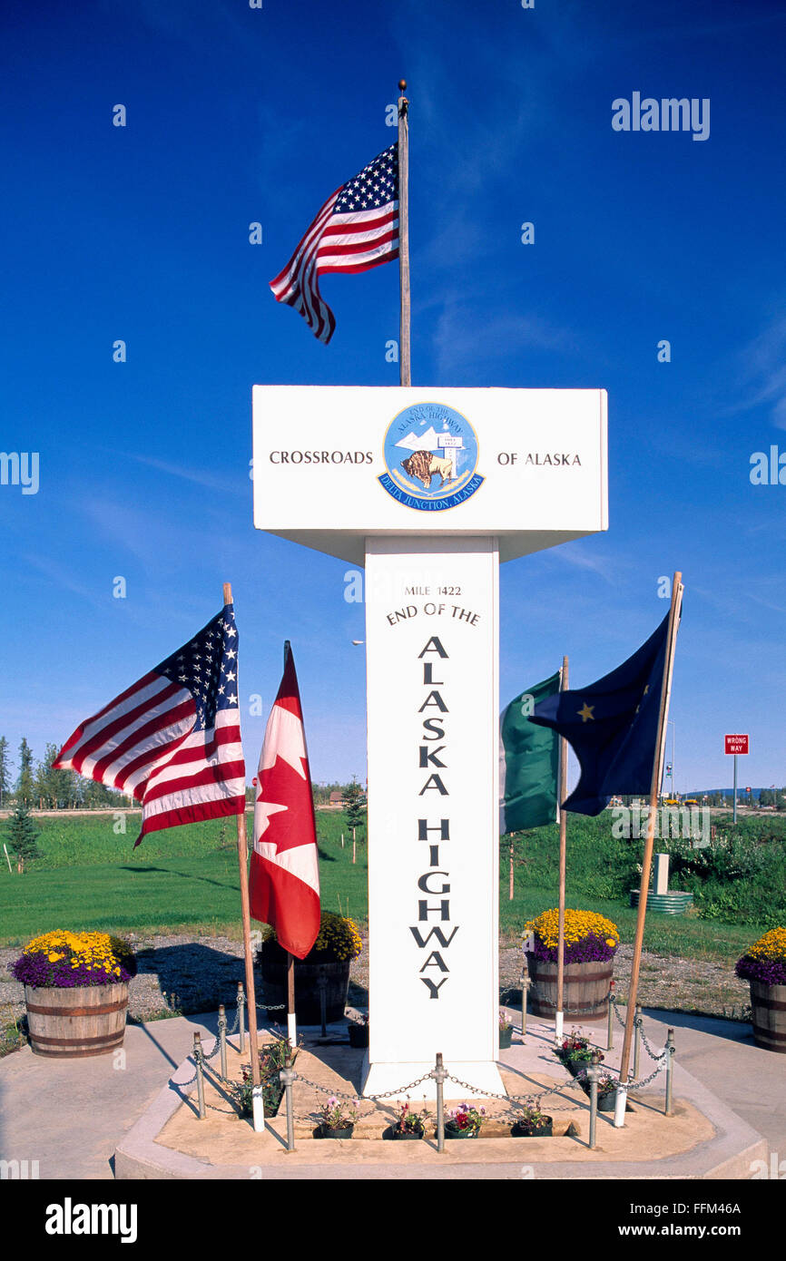 Delta giunzione, Alaska, Stati Uniti d'America - Miglio 1422, fine dell'Alaska Highway Signpost circondato dagli americani, canadesi e bandiere in Alaska Foto Stock