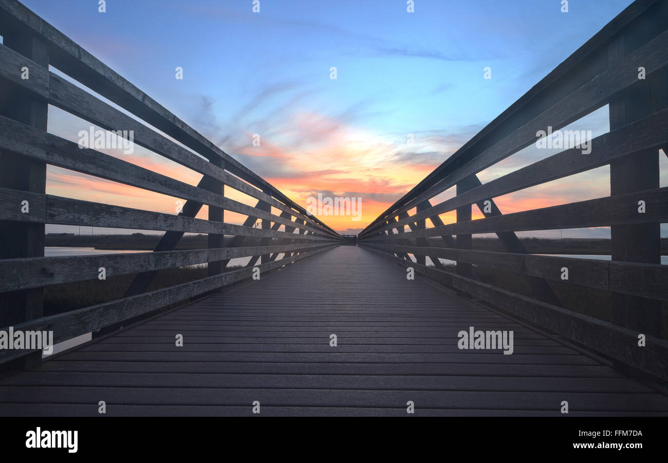 Passerella in legno al tramonto, per viaggio attraverso Bolsa Chica zone umide di preservare in Huntington Beach, California, Stati Uniti Foto Stock