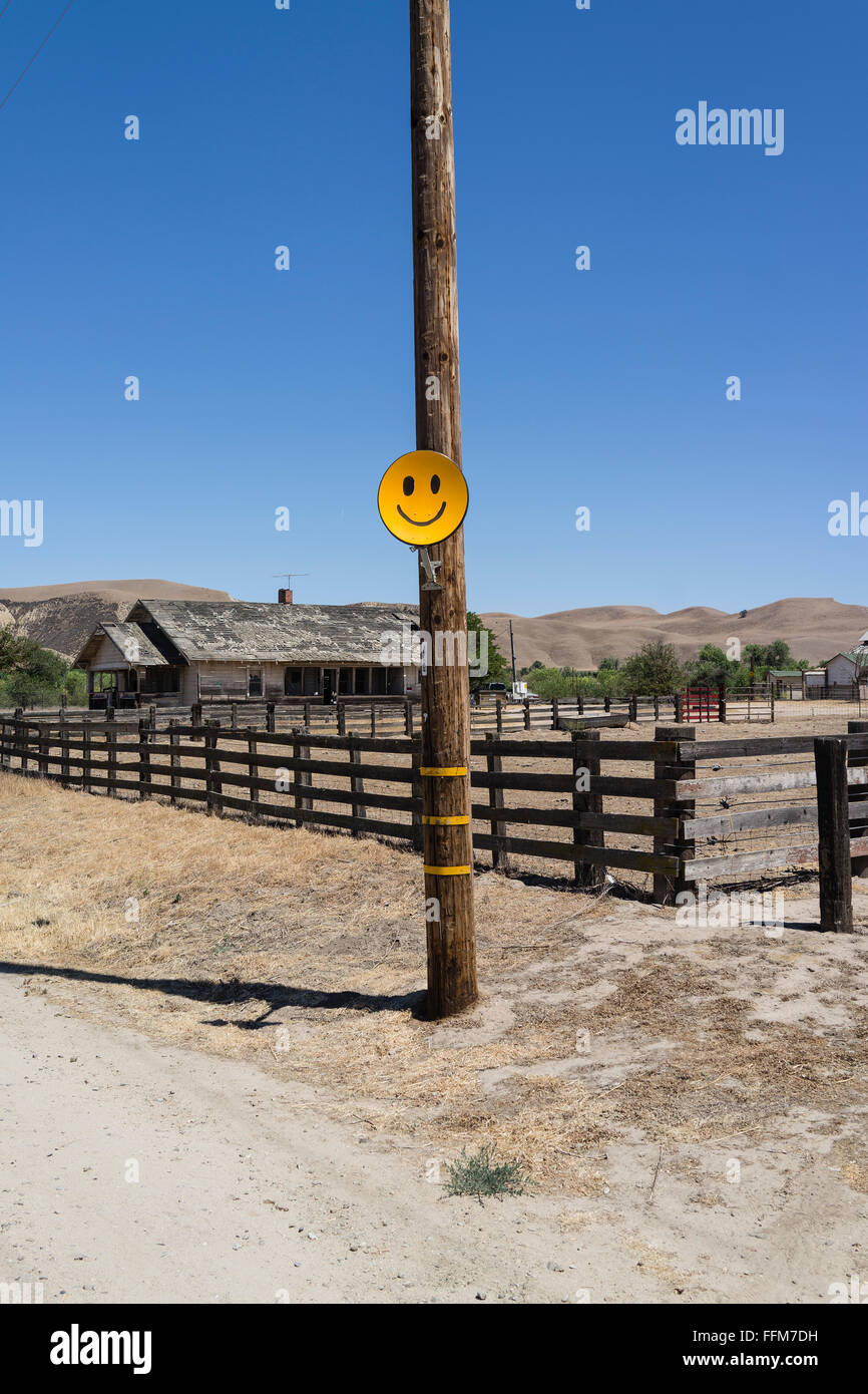 Un giallo arancio Smiley face antenna satellitare collegato ad un telefono in legno in pole nella valle centrale della California. Foto Stock