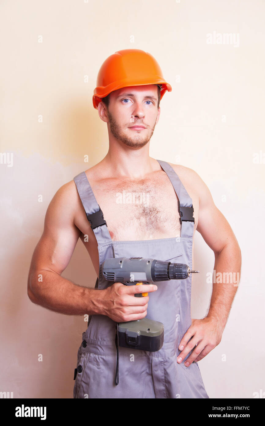 Un uomo in tuta e casco con un cacciavite Foto Stock