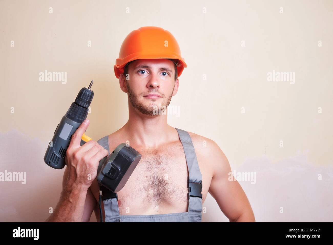 Un uomo in tuta e casco con un cacciavite Foto Stock