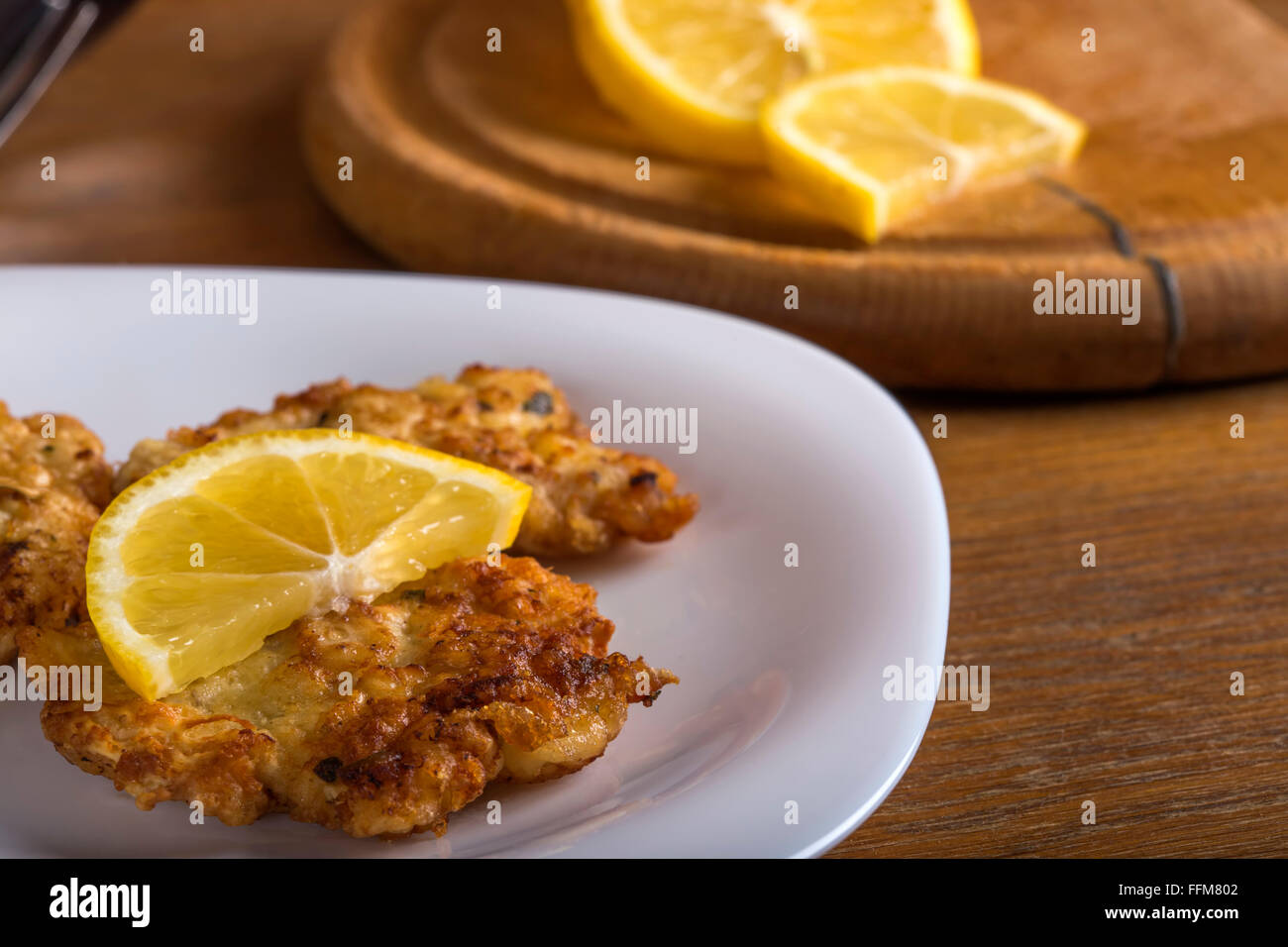 Cotoletta di pollo con spicchi di limone in piastra bianca Foto Stock