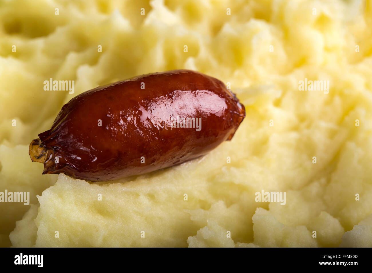 Un piccolo salsicce di maiale su purea di patate Foto Stock