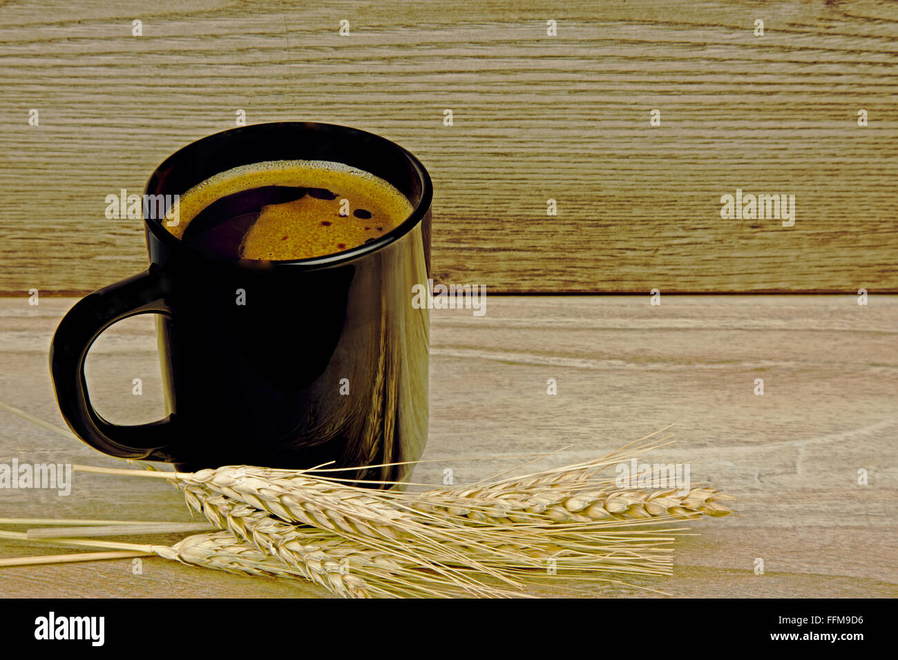 Tazza di caffè di cereali grano con due spighe di grano di mais cereali giacenti accanto a un vecchio tavolo di legno. Vista orizzontale. Foto Stock