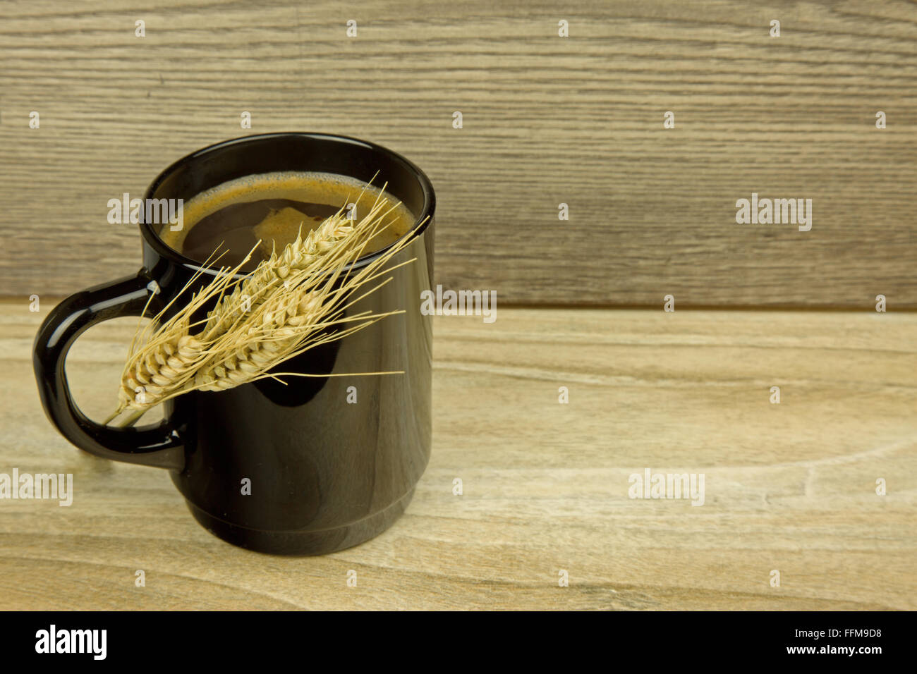 Tazza di caffè di cereali grano con spighe di grano di mais prodotti a base di cereali in verticale sulla tazza , sul vecchio tavolo in legno. Vista orizzontale. Foto Stock