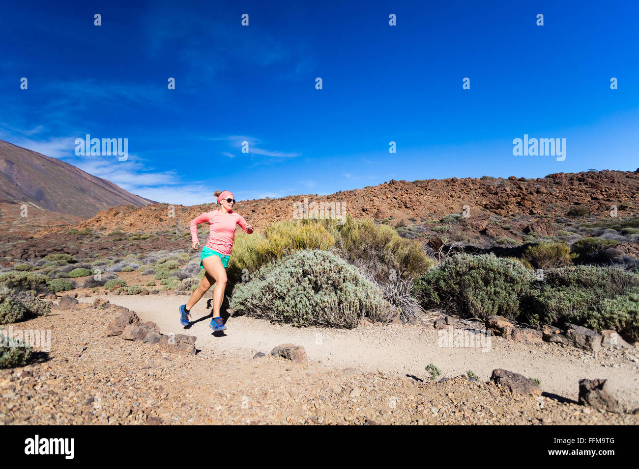 Giovane donna in esecuzione in montagna su soleggiate giornate estive. La bellezza femminile jogging ed esercitando all aperto in natura, trail run Foto Stock