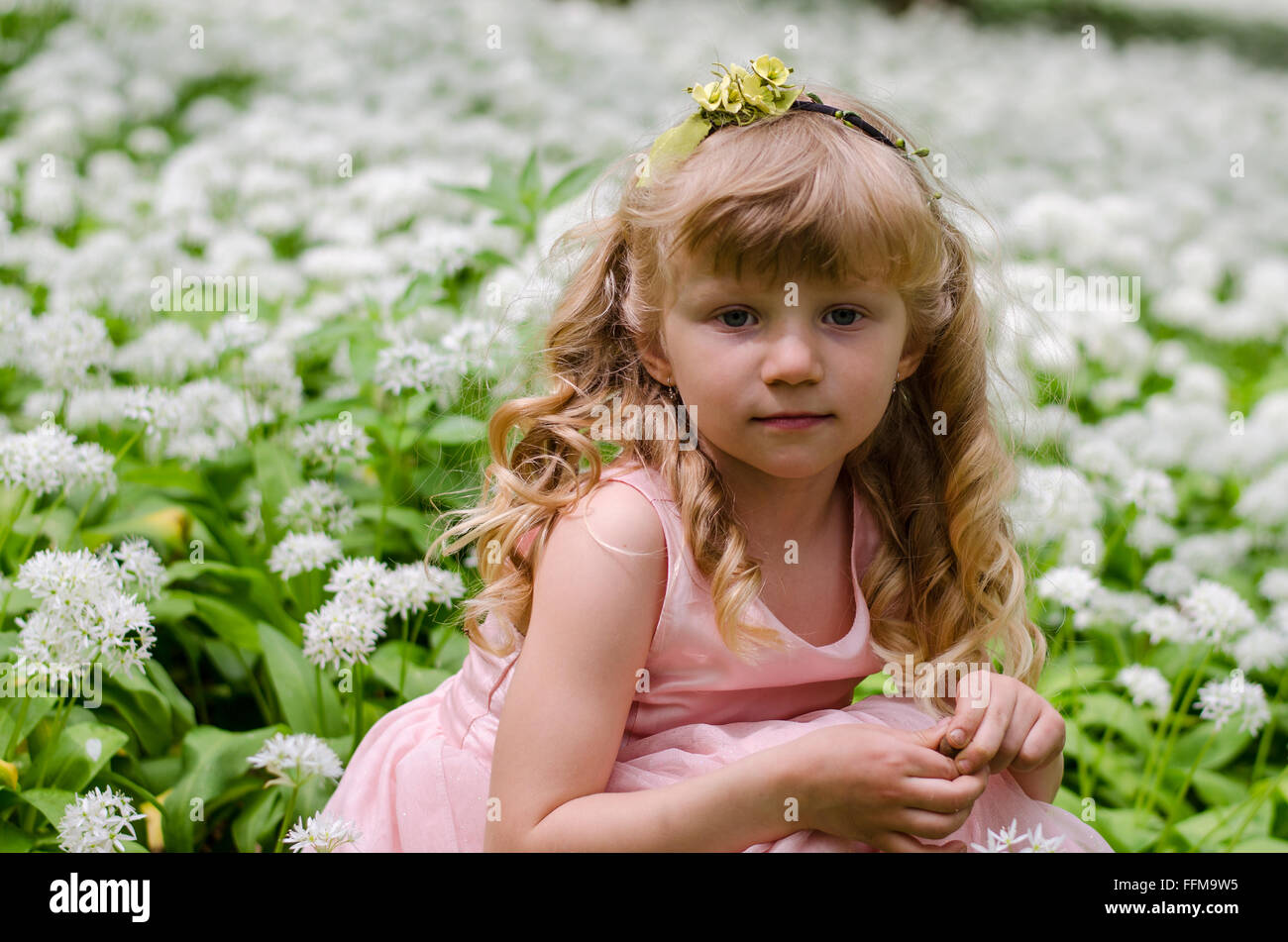 Adorabile ragazza bionda principessa seduto tra i fiori bianchi Foto Stock