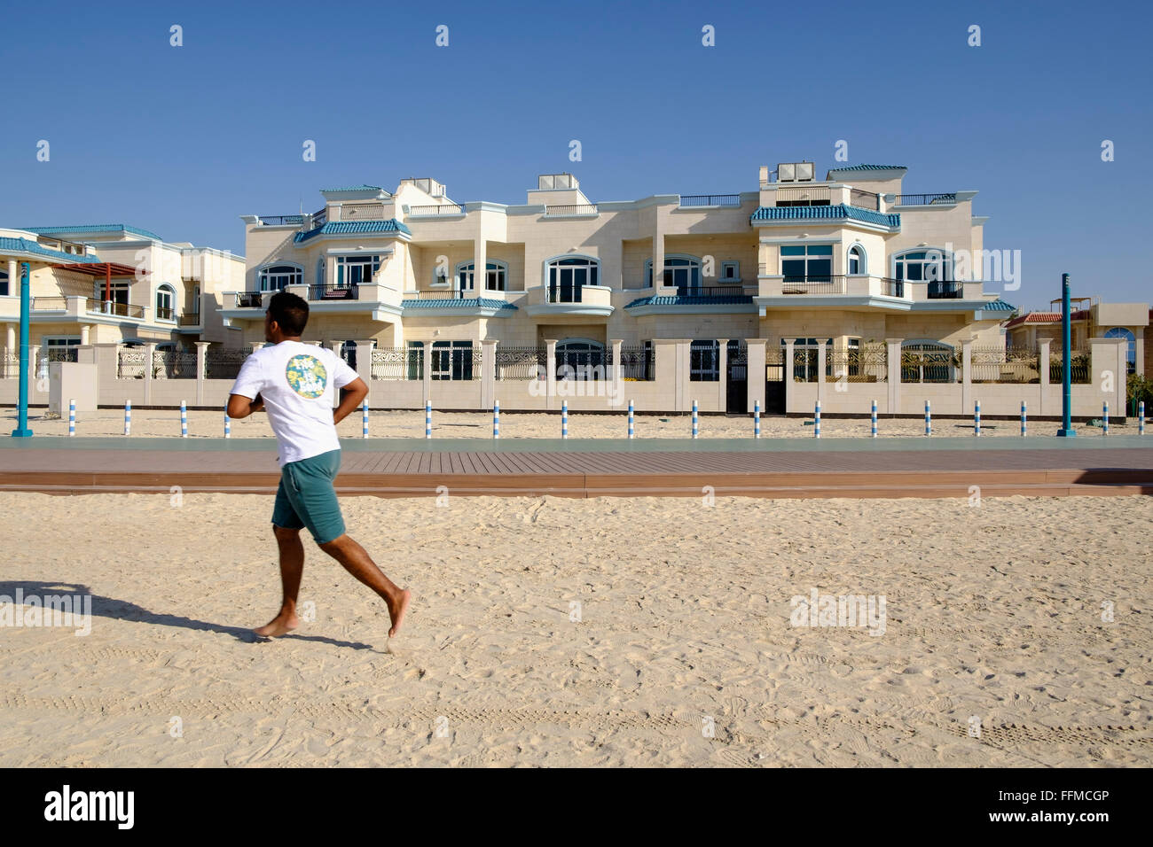Uomo passato jogging ville di lusso affacciato sulla spiaggia in Dubai Emirati Arabi Uniti Foto Stock