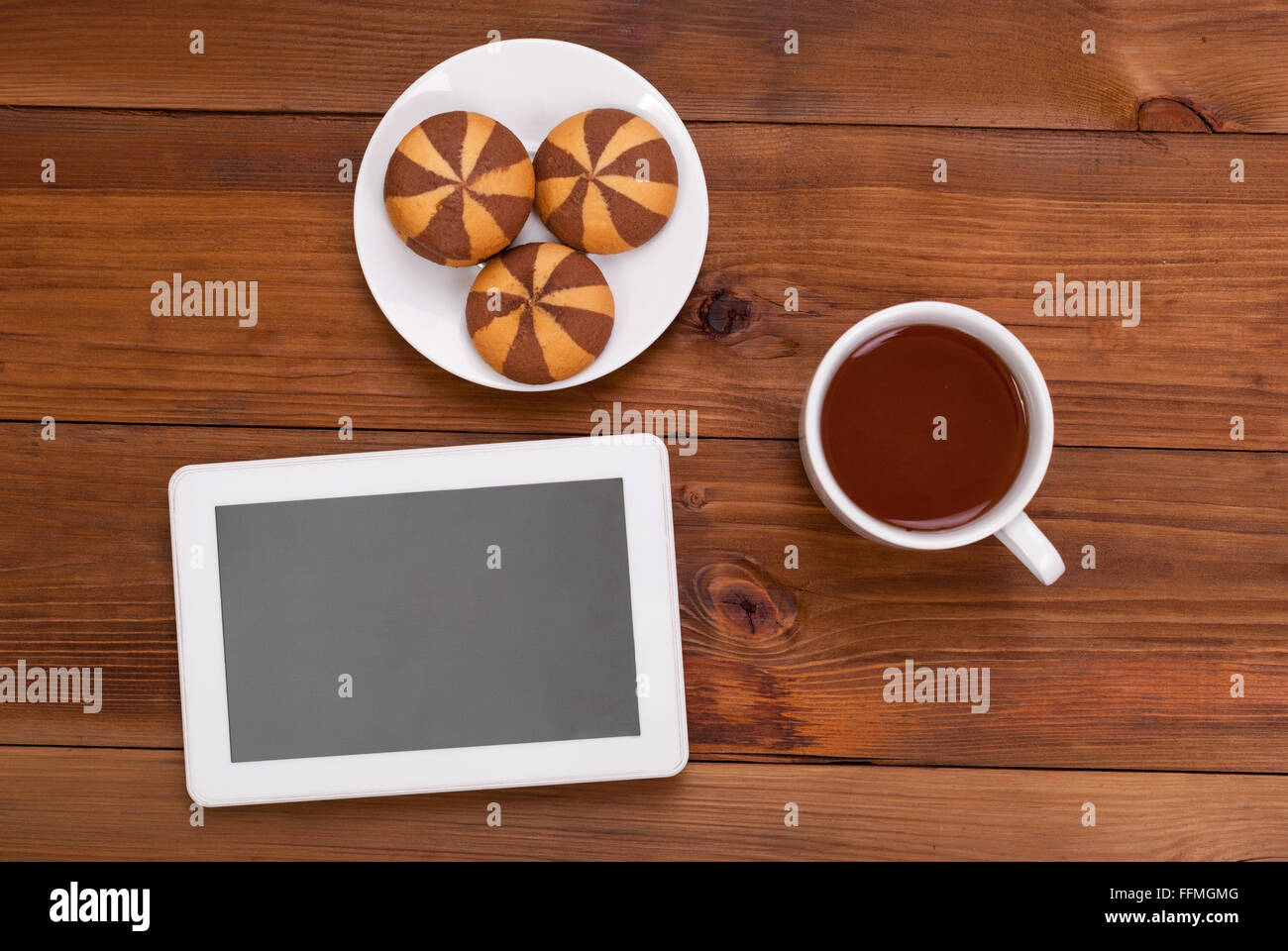 Tazza di tè e biscotti una tavoletta digitale sul tavolo di legno. Vista superiore . Foto Stock