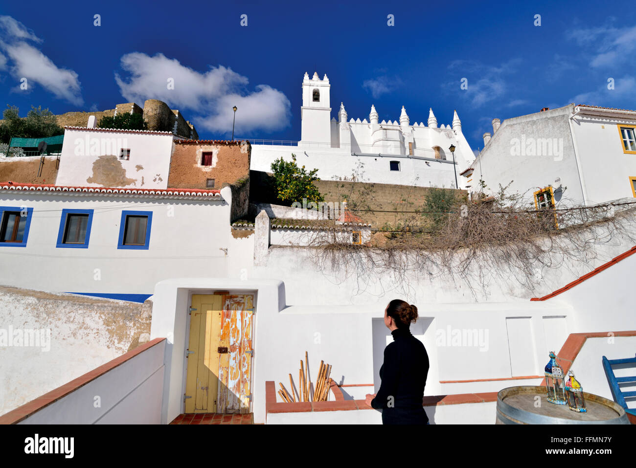 Portogallo Alentejo: Donna guardando dal terrazzo per la chiesa e il castello di villaggio storico Mértola Foto Stock