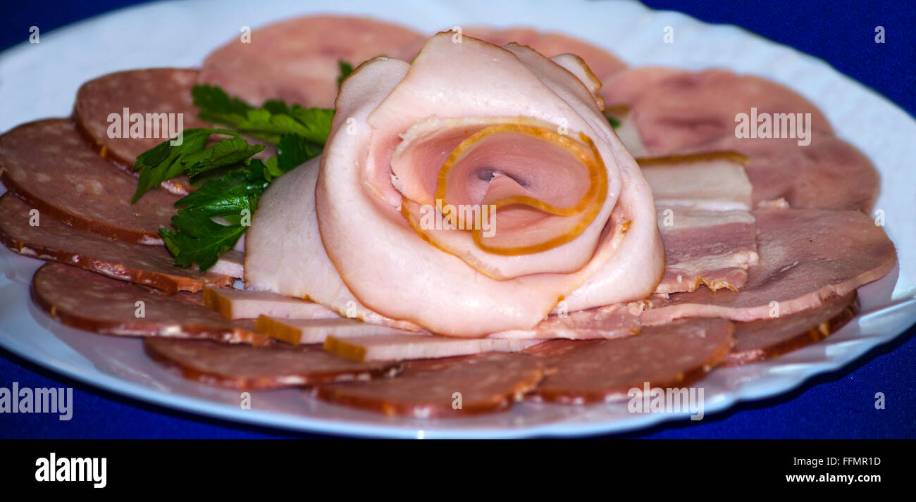 I prodotti a base di carne sono tagliate a fettine su una piastra bianca, prodotti a base di carne, salsicce, carne, alimentare, un prodotto su uno sfondo blu Foto Stock