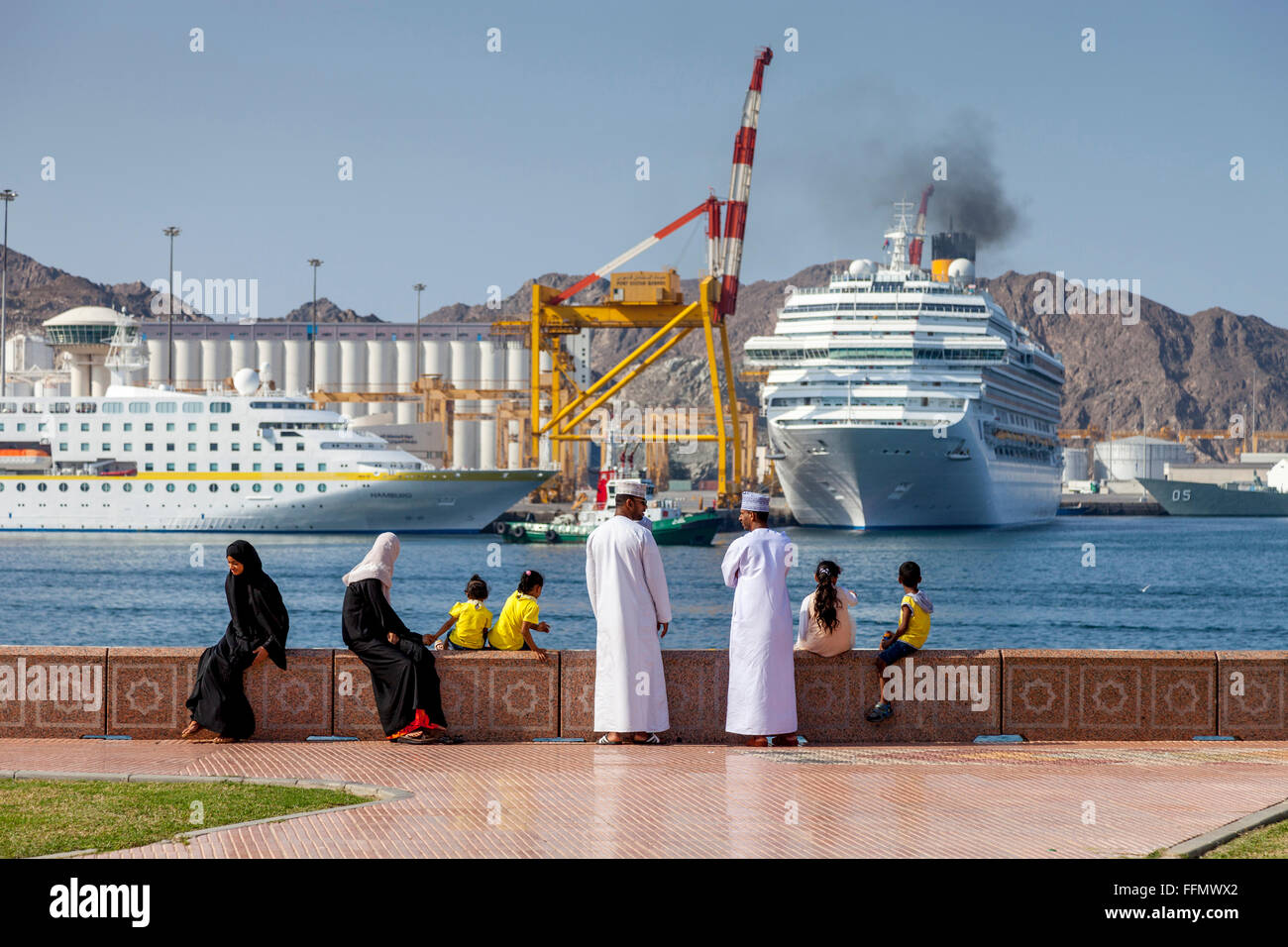 Una famiglia Omani guardare le navi da crociera di lasciare il porto di Muttrah, Moscato, il sultanato di Oman Foto Stock