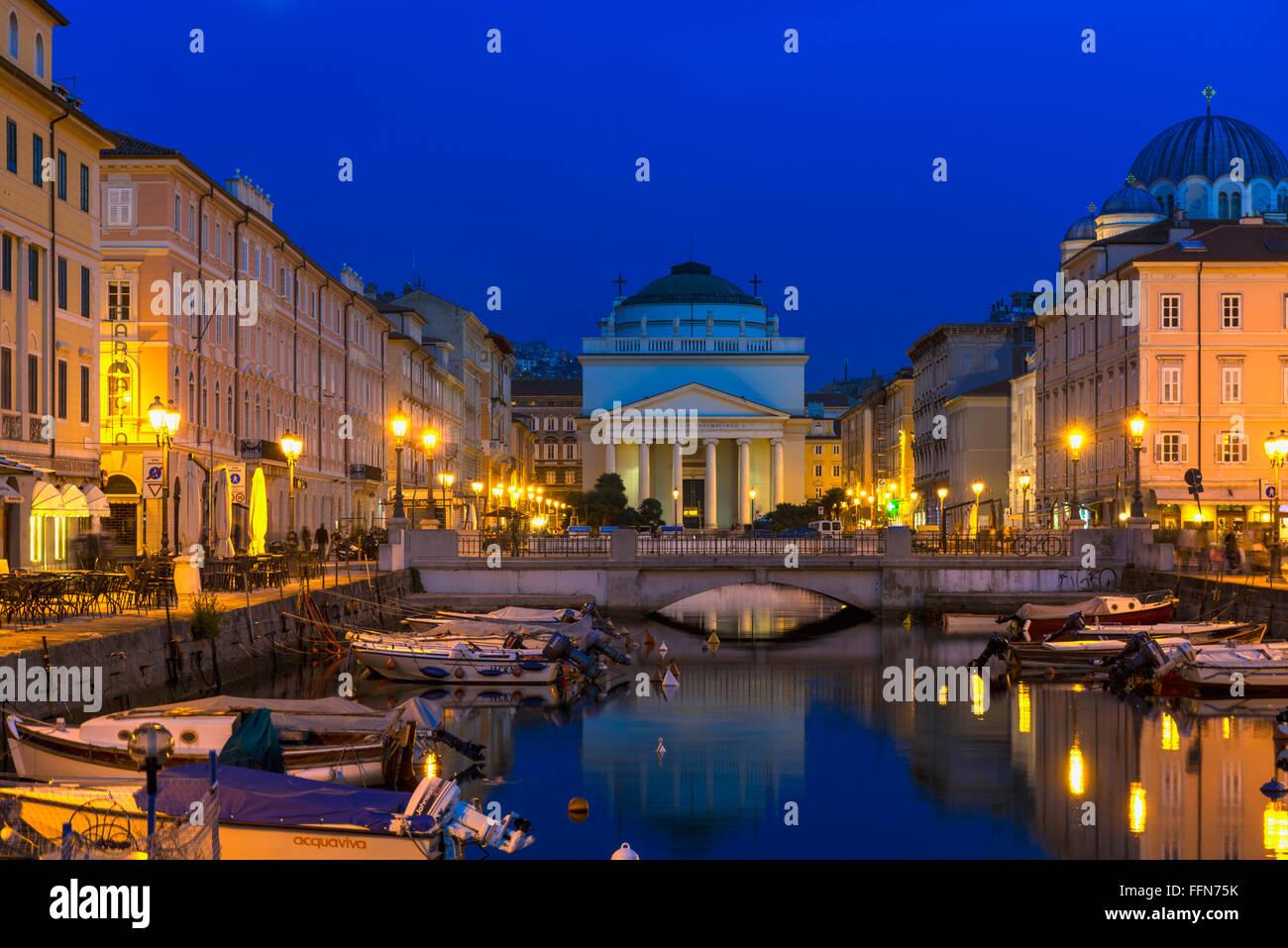Il Grand Canal, Trieste, Italia, Europa - con vecchi edifici storici e barche illuminate sul lungomare Foto Stock