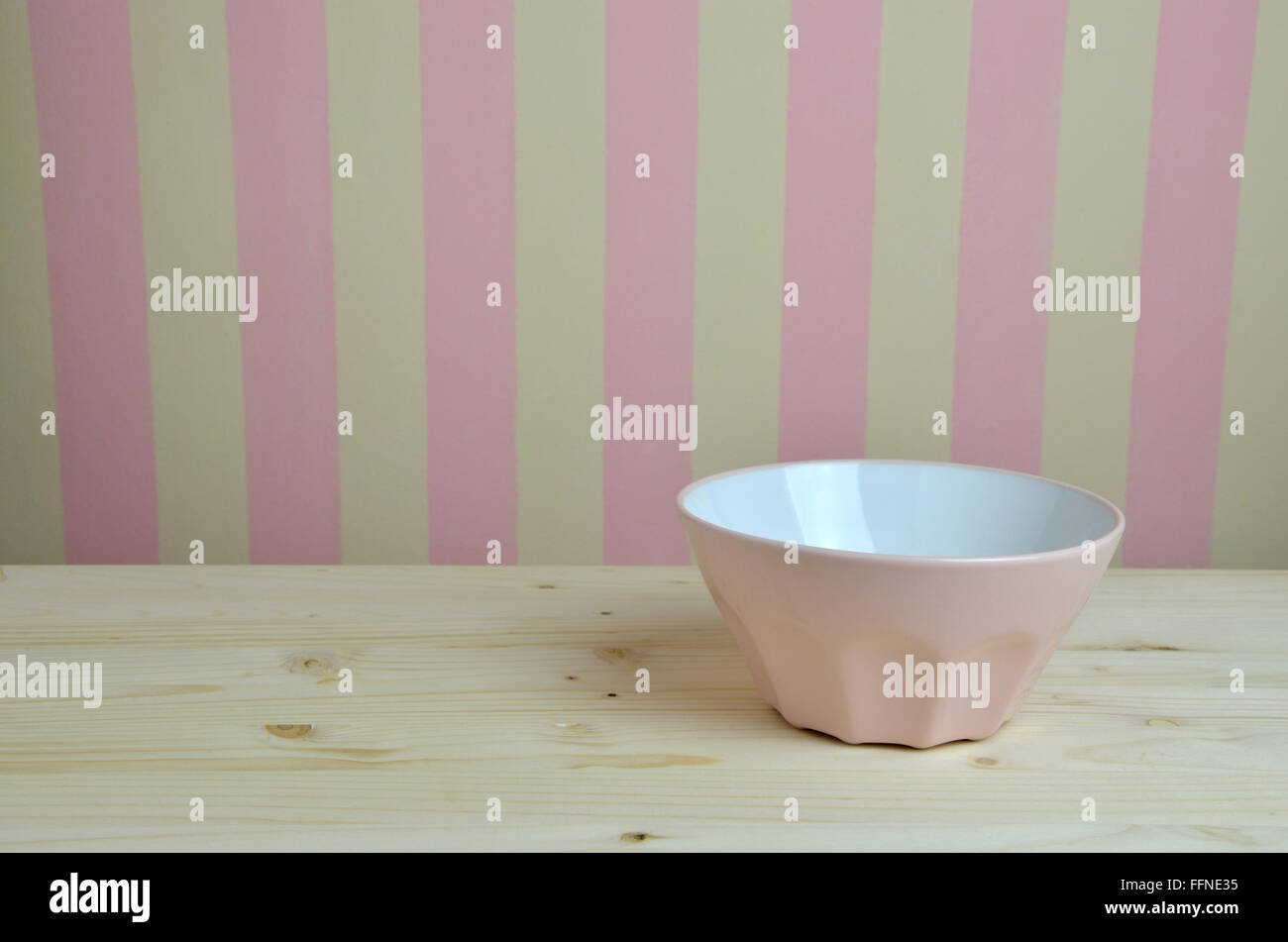 Ciotola rosa sul tavolo di cucina e di rosa-parete gialla in background Foto Stock