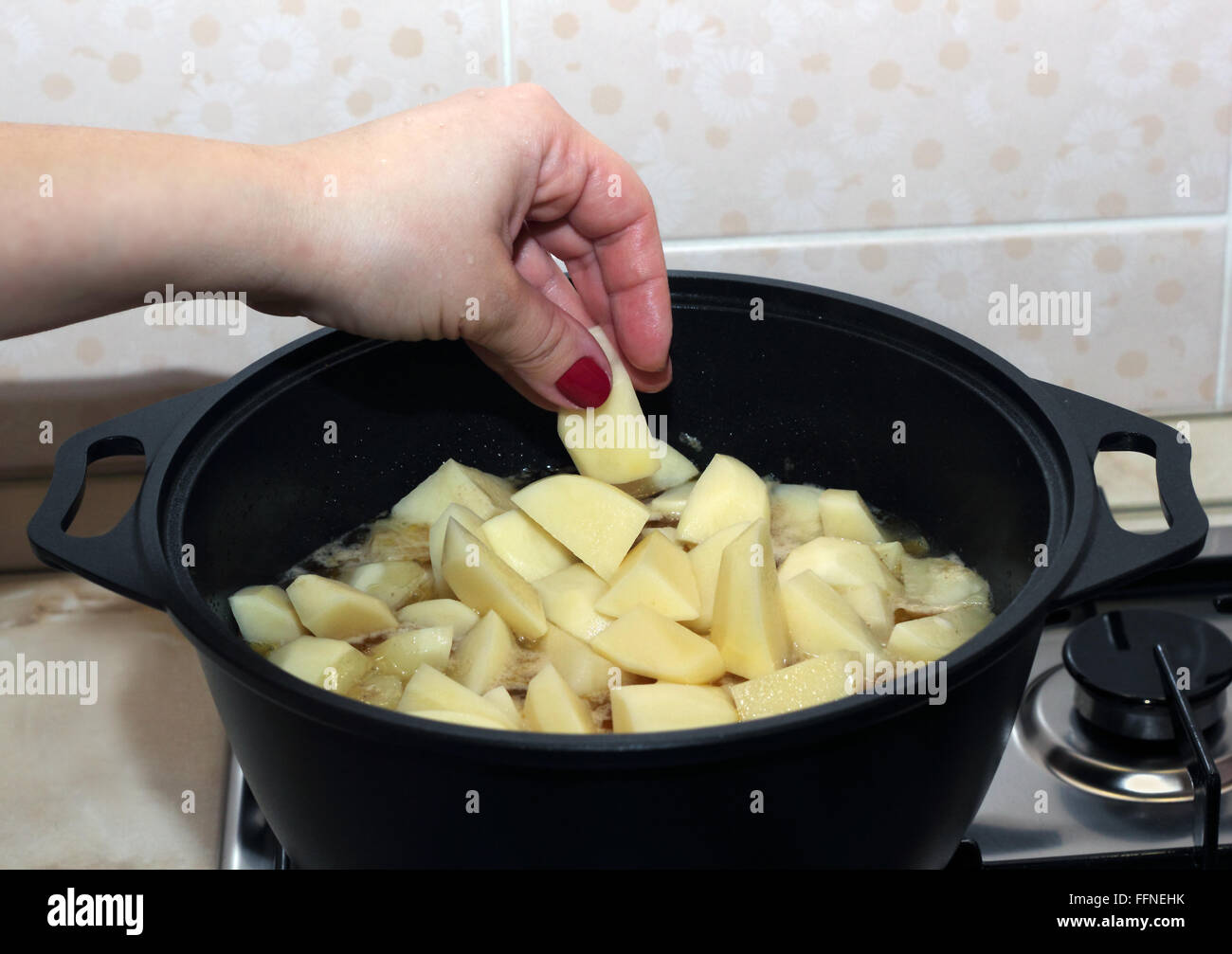 Donna di mettere mano una patata le piastrine in metallo nero pot Foto Stock