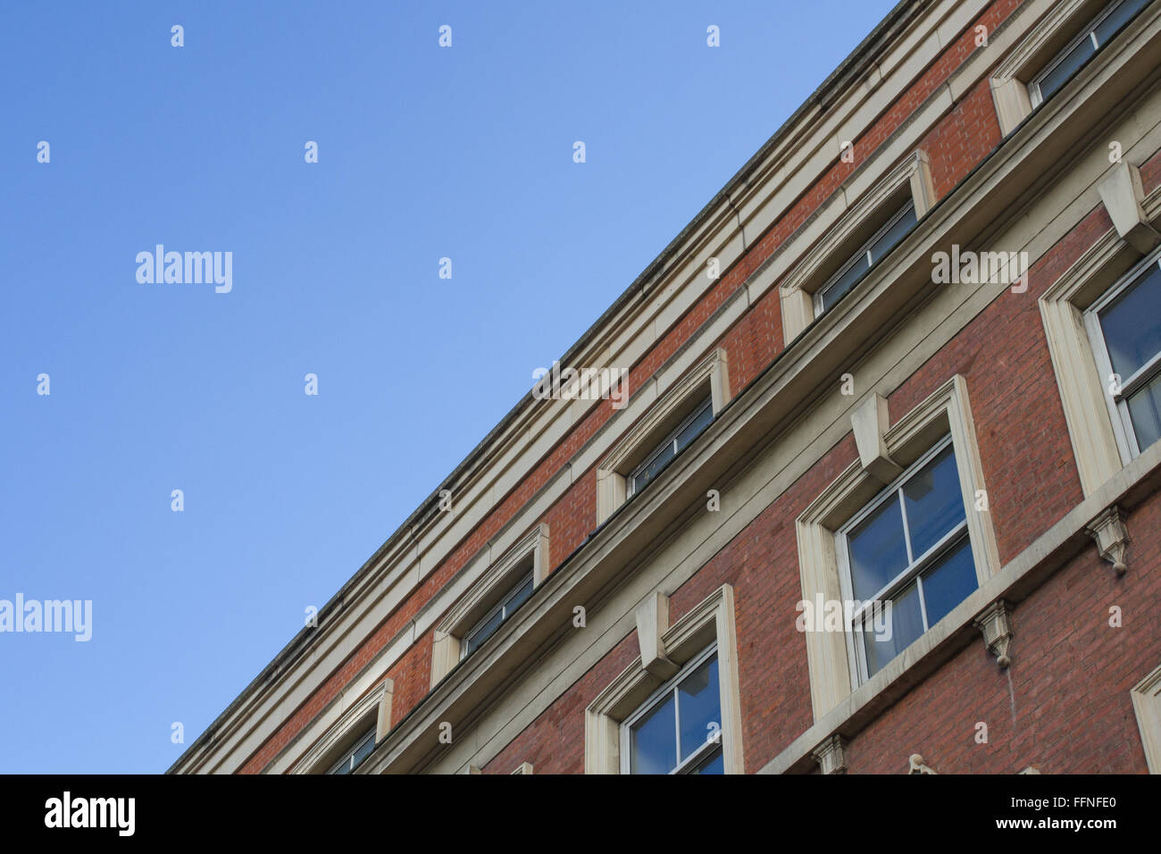 Una vista dalla terra alla ricerca fino al tetto e la facciata di un solido, un edificio del periodo con mattoni rossi e file di windows. Foto Stock
