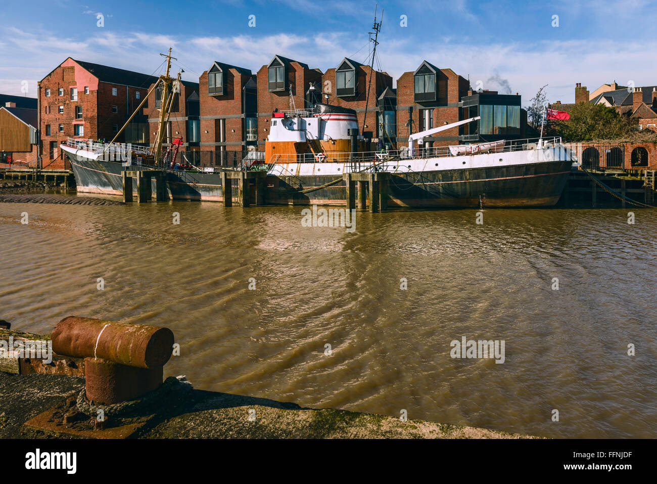 Fiume scafo ad alta marea con un obsoleto peschereccio nel fango bank affiancato da ufficio e di altri edifici di Hull, Yorkshire Foto Stock