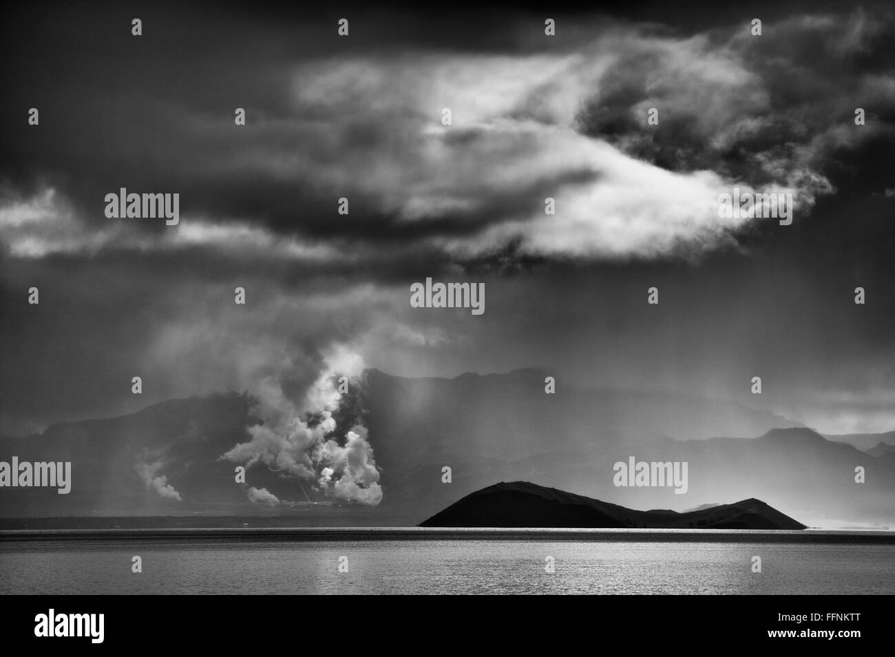 L'isola Sandey al lago Thingvallavatn, sud dell'Islanda. Il vapore proveniente dalla geotermia piano in Nesjavellir, Foto Stock