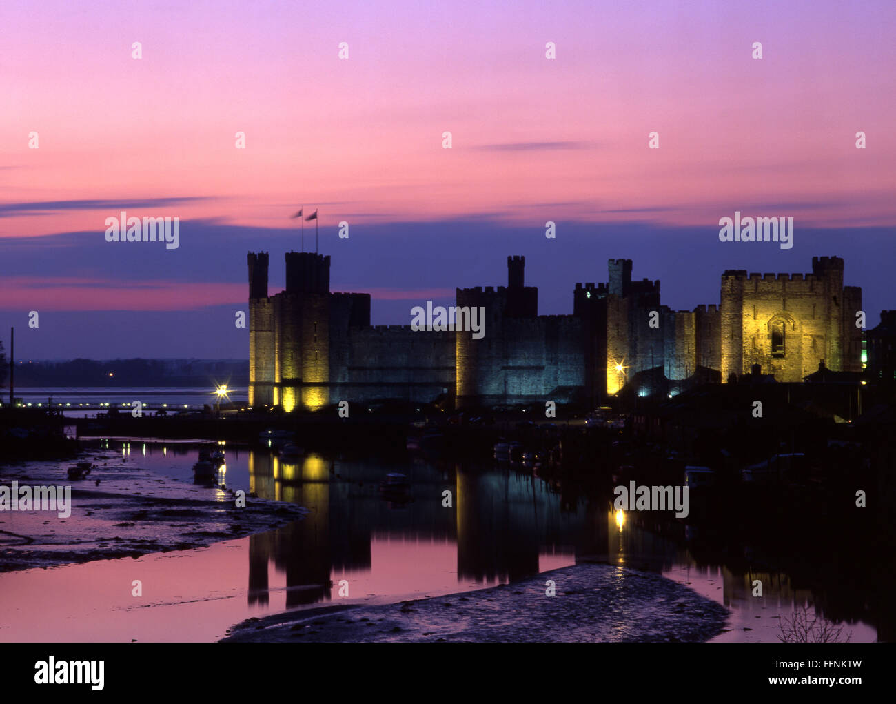 Caernarfon Castle al tramonto tramonto crepuscolo la notte con il fiume Seiont a bassa marea Gwynedd North Wales UK Foto Stock