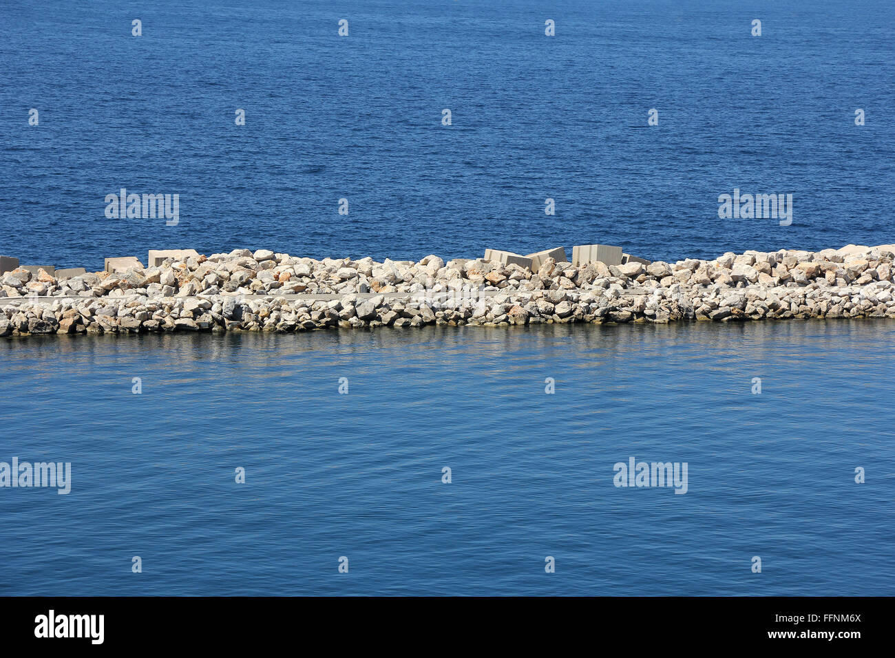 Massello di pietra e la diga di cemento sul mare Foto Stock
