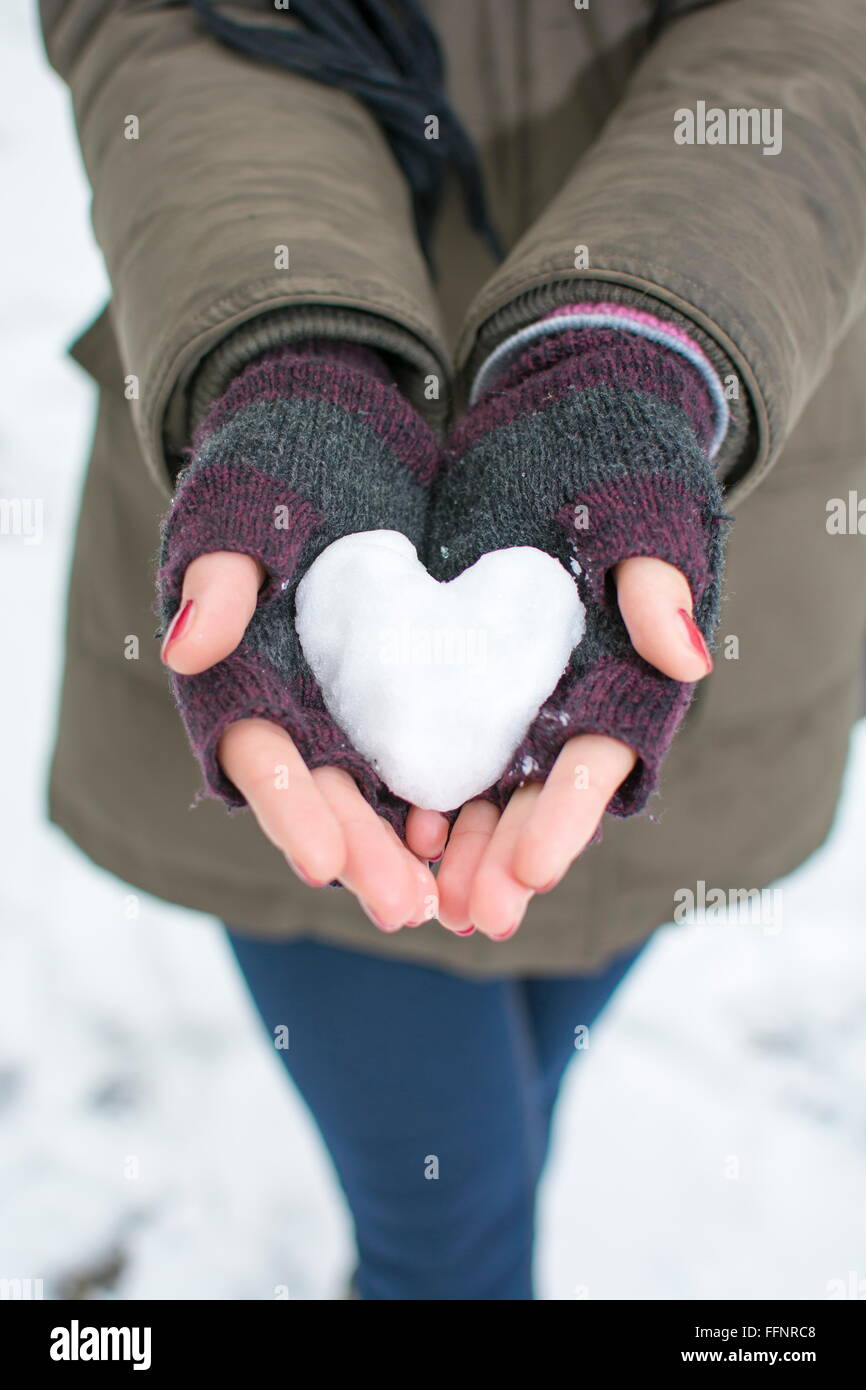 Donna che mantiene a forma di cuore ad snowball Foto Stock