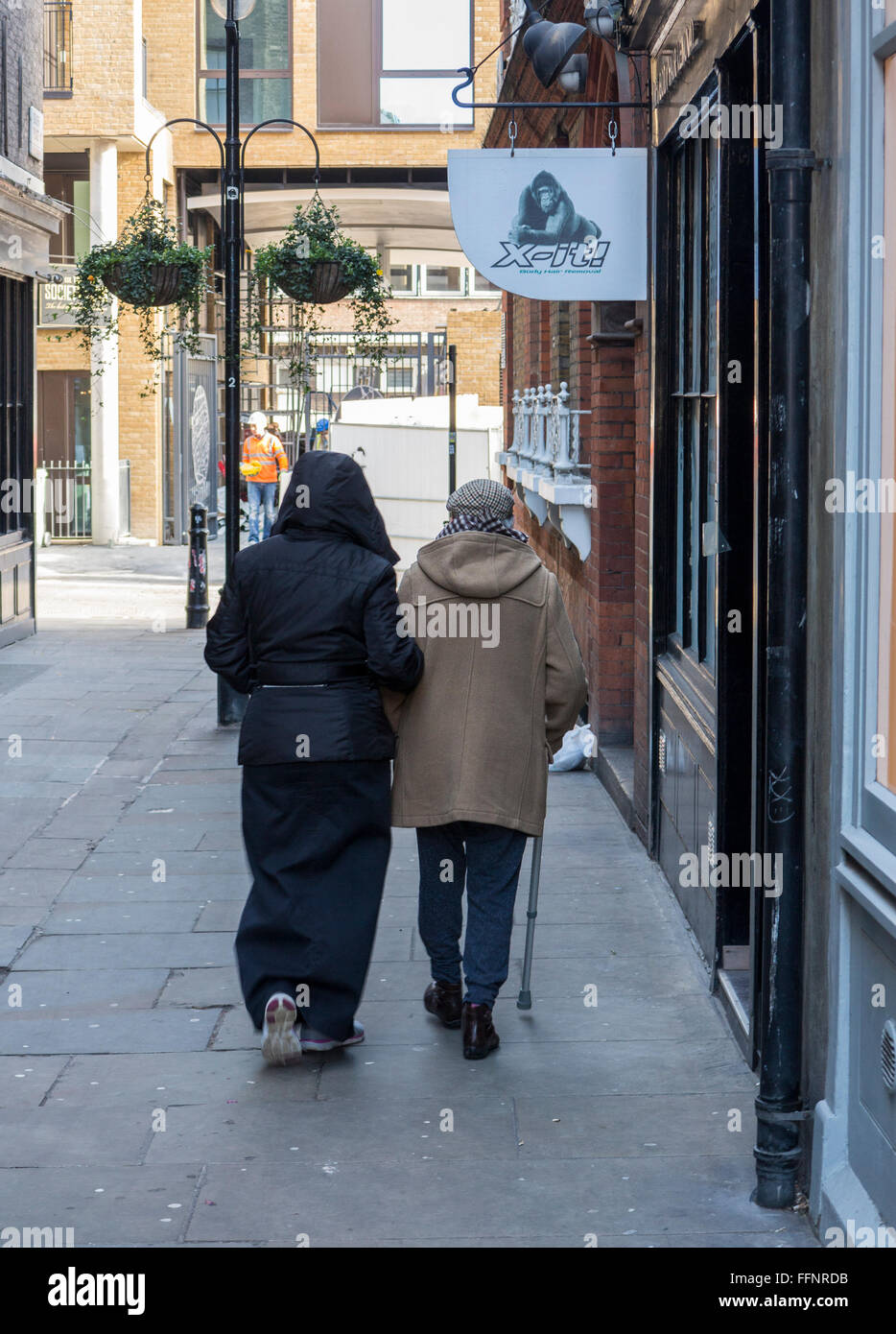 Una donna musulmana aiuta un uomo anziano in una passeggiata Foto Stock