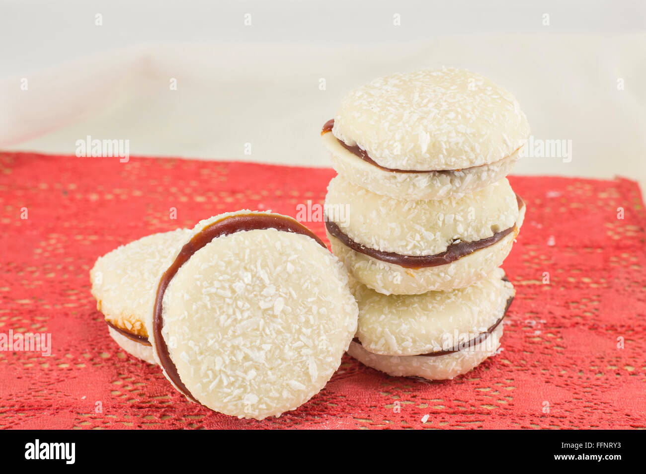 I cookie di bianco con noce di cocco e marmellata su una superficie di colore rosso Foto Stock