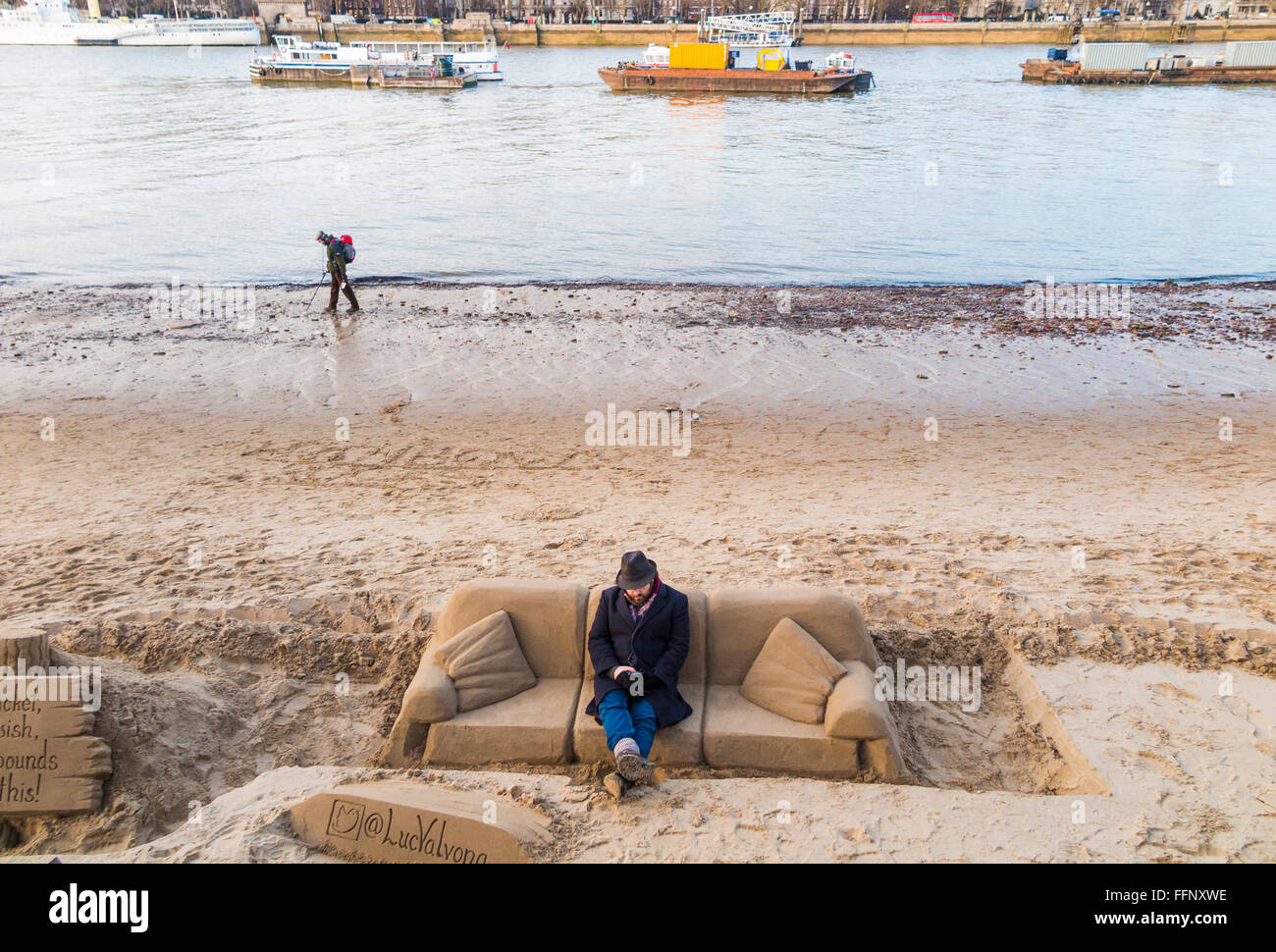 Scultore seduto su un divano di sabbia scultura lungo gli argini del fiume Thames, London a bassa marea Foto Stock