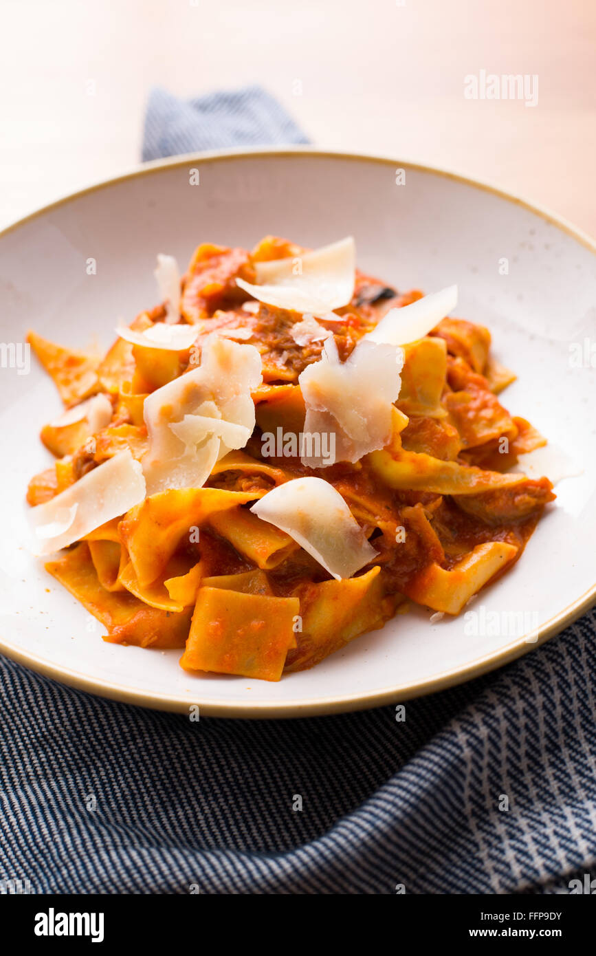 Pappardelle in una marinara con carnitas e grava padano in un luminoso ristorante l'impostazione. Foto Stock